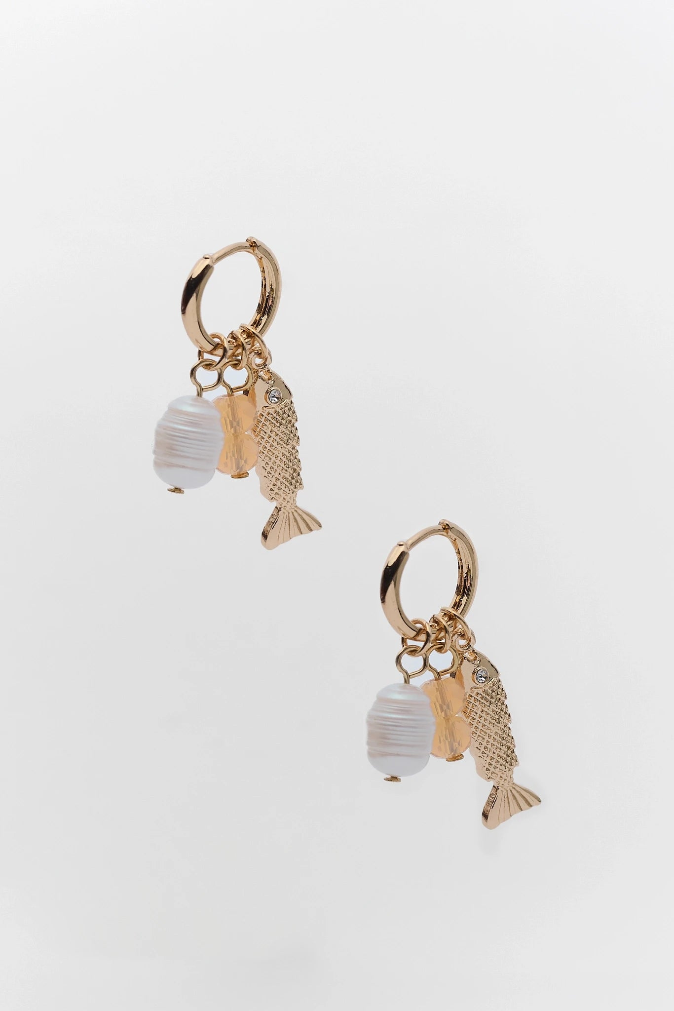 Pair of gold and silver fish-shaped earrings on a white background