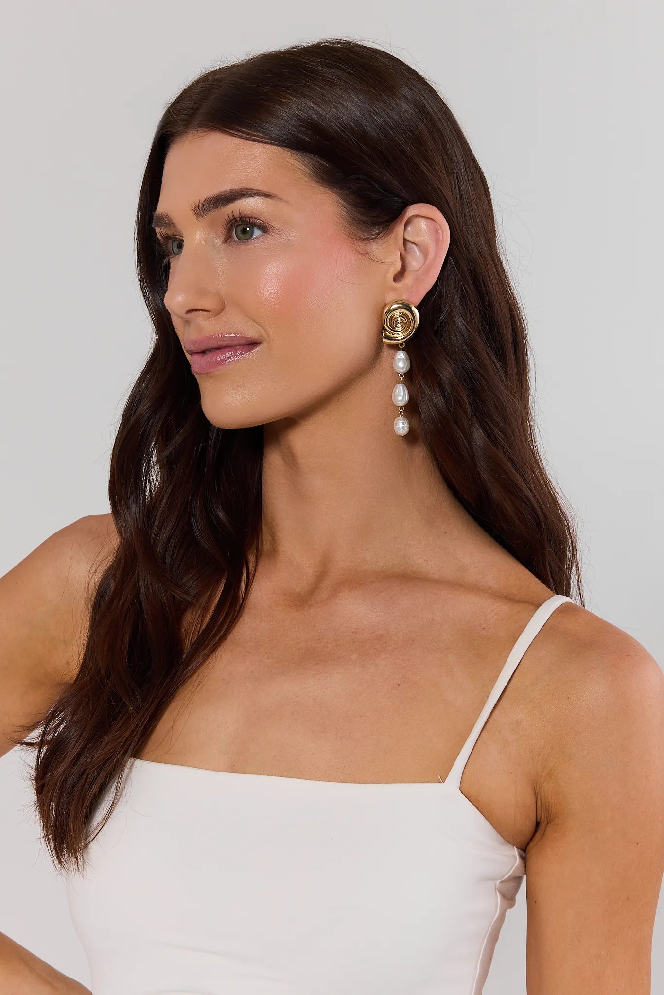 Woman wearing pearl earrings against a plain background