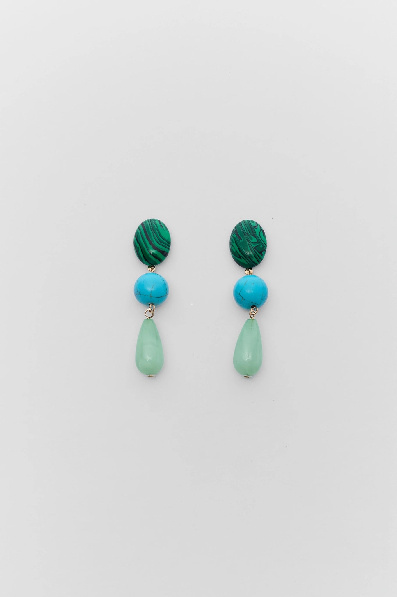 Pair of earrings with green and blue beads on a light gray background