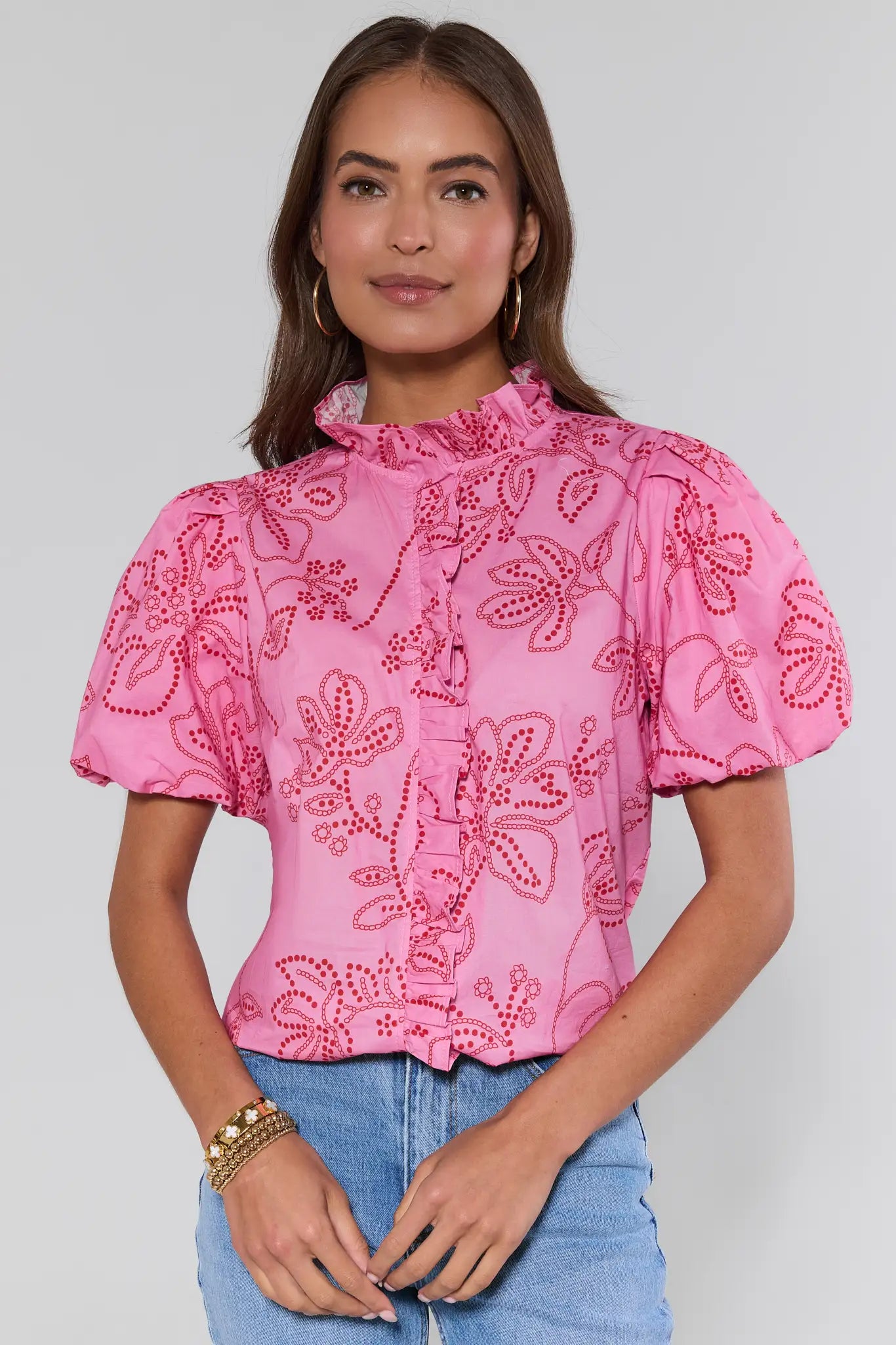 Woman wearing a pink blouse with floral patterns on a plain background