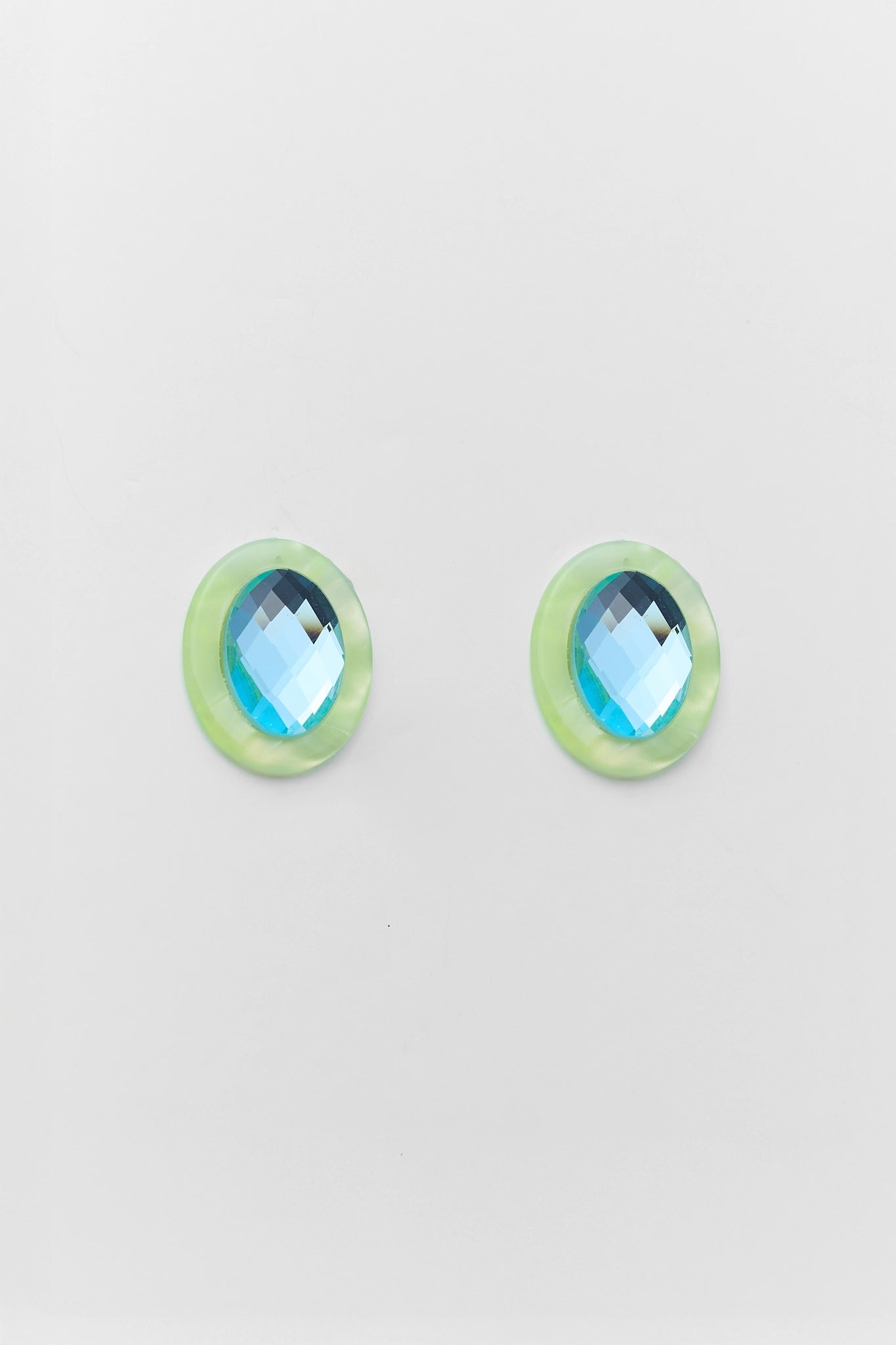 Pair of green earrings with blue gemstones on a light gray background