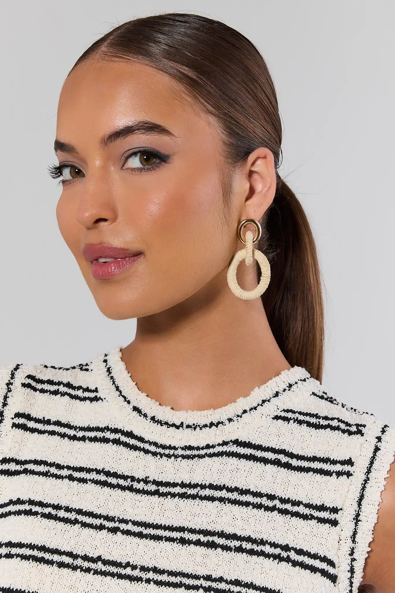 Woman wearing large hoop earrings with a neutral background