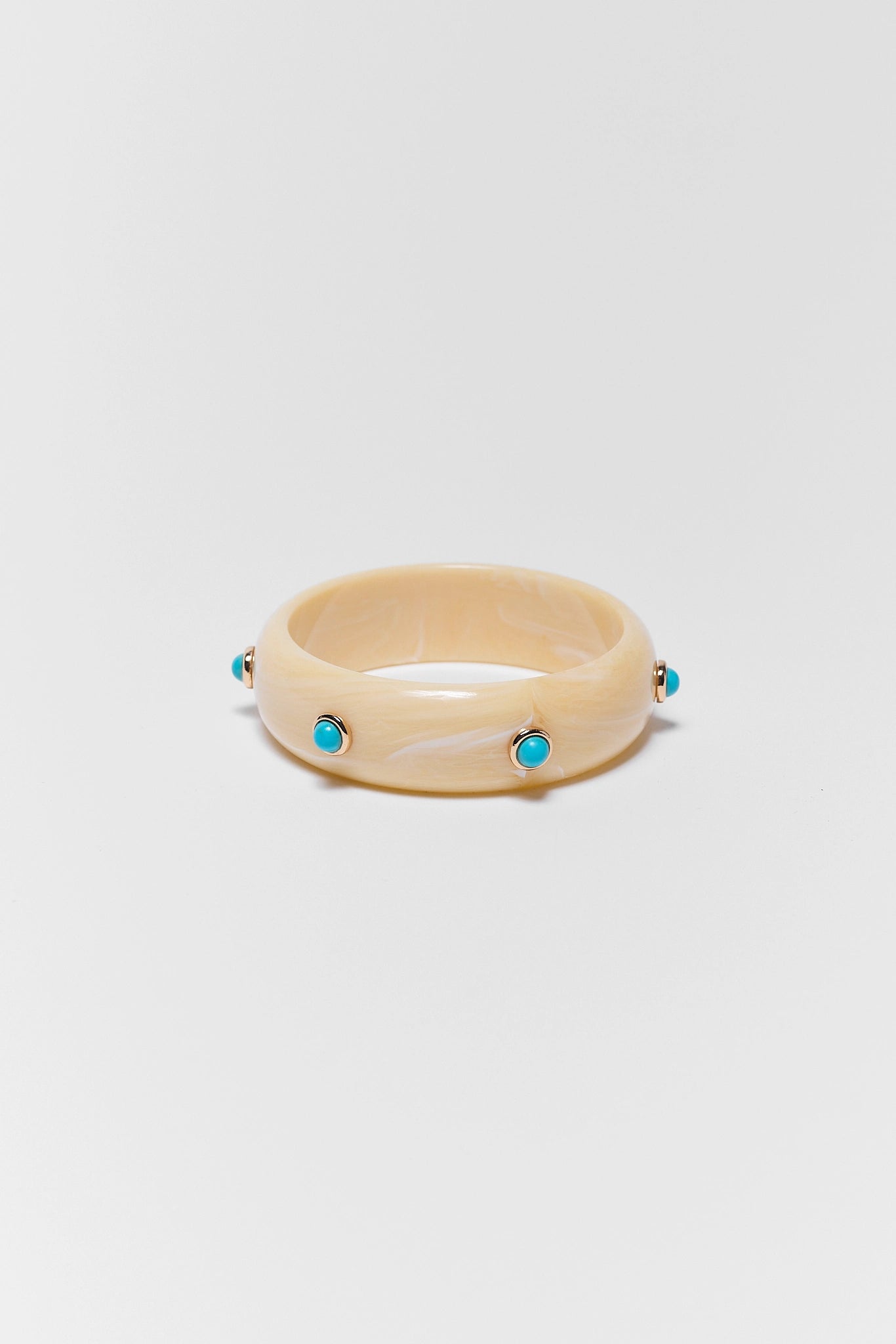 Beige ring with turquoise stones on a light gray background
