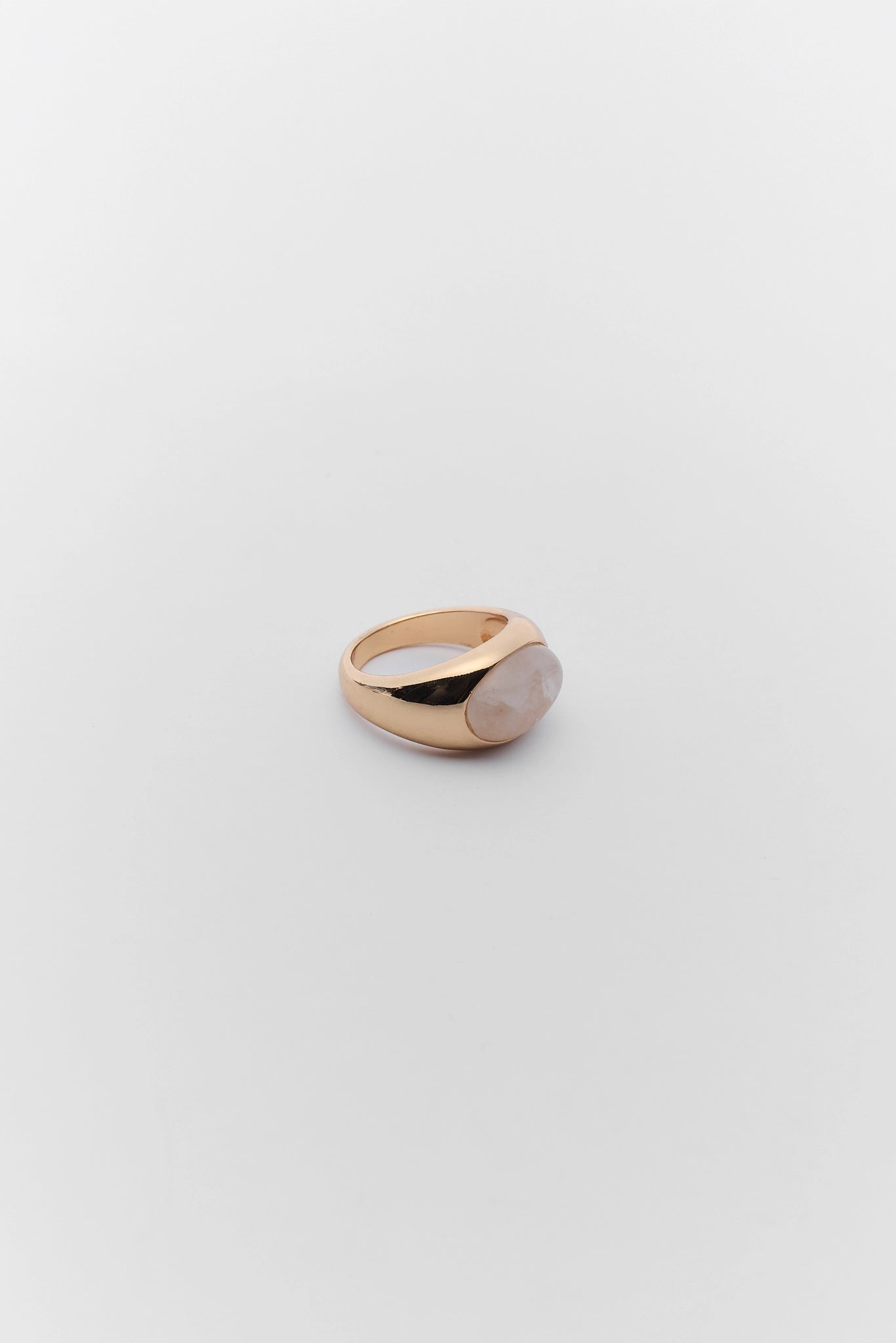 Gold ring with a pink stone on a light gray background