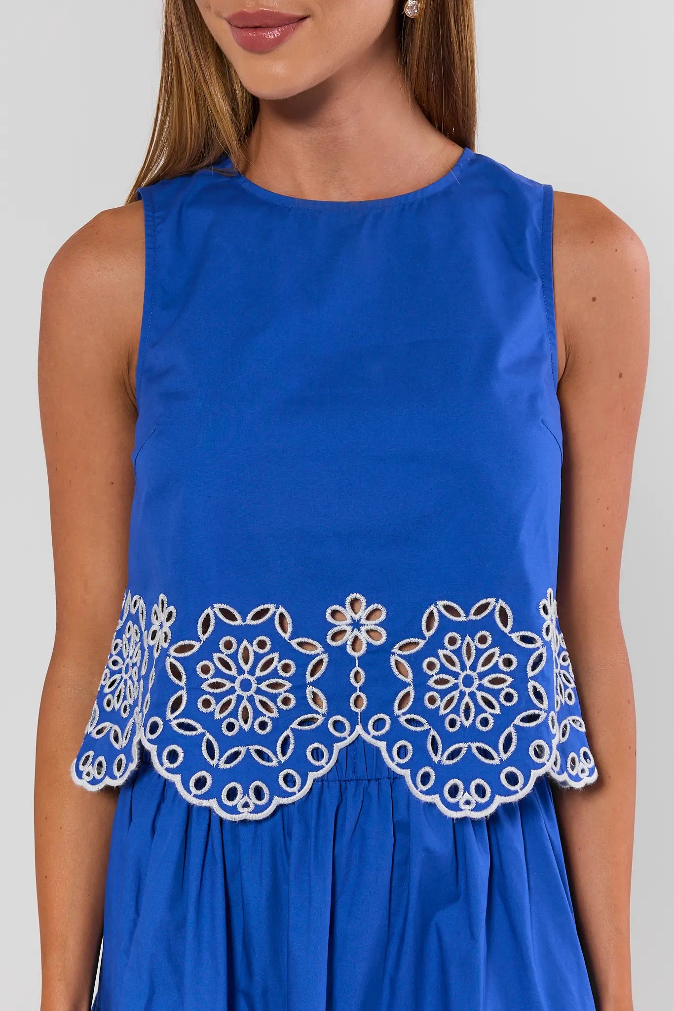Blue dress with white lace details on a plain background close up