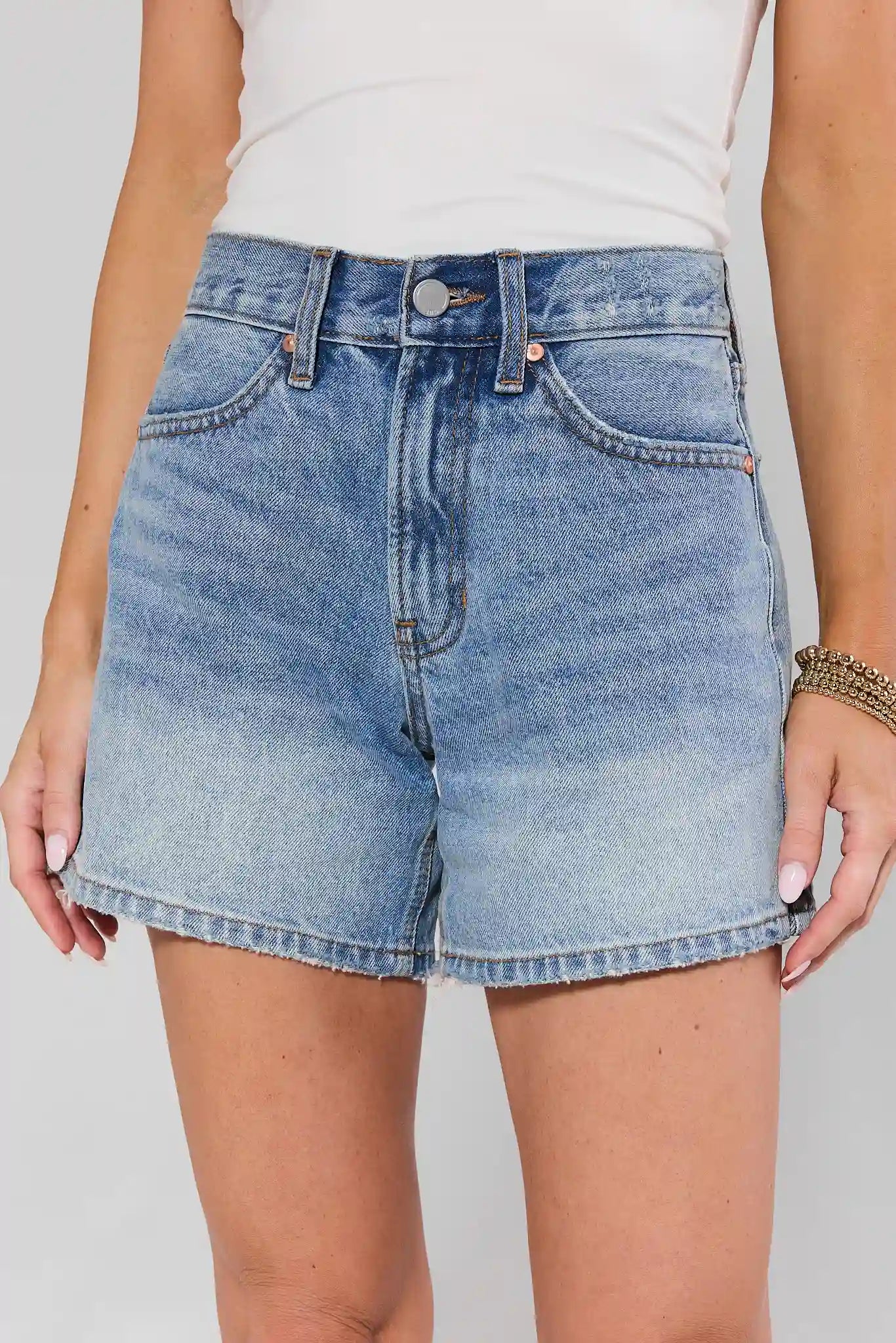 Denim shorts worn by a person on a plain background