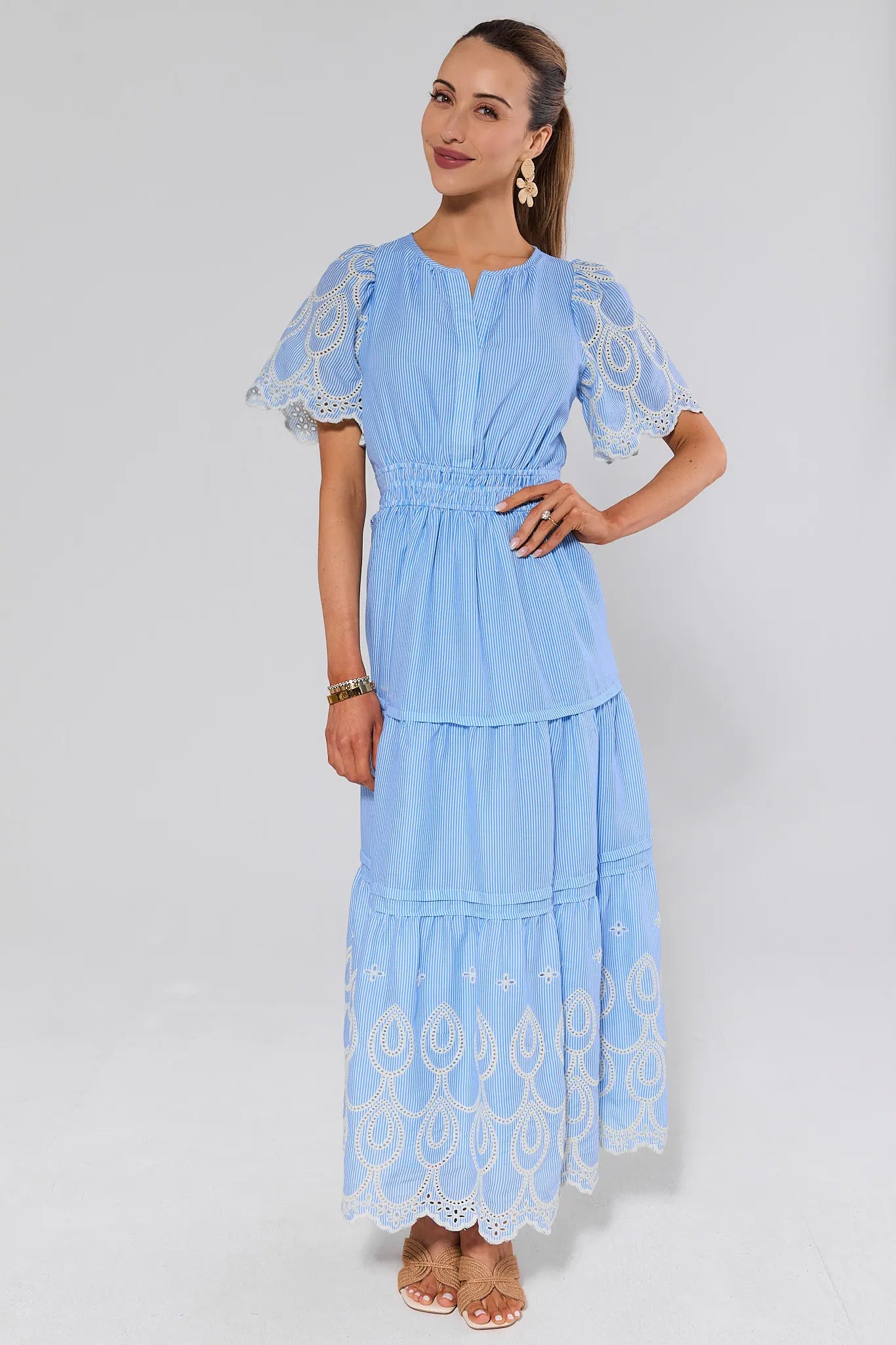 Woman wearing a light blue dress with lace details and heels on a white background