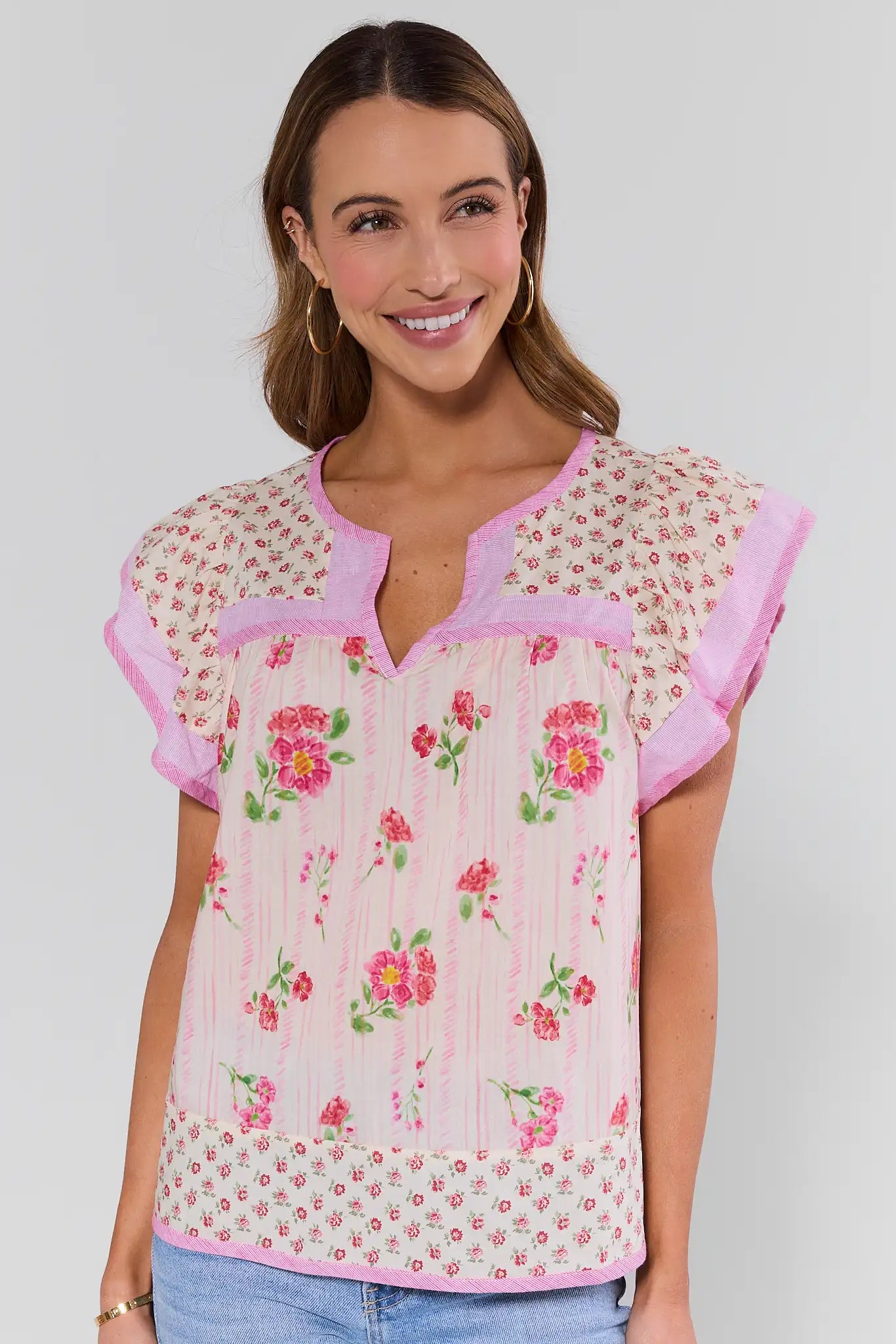 Woman wearing a floral blouse with pink accents on a plain background