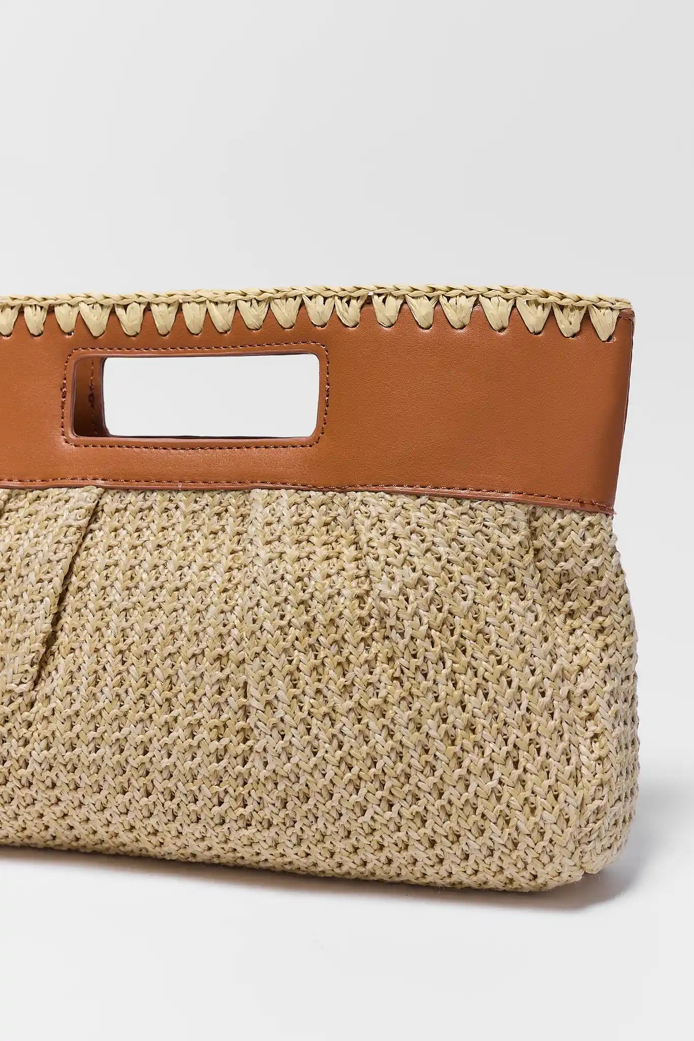 close up Woven handbag with brown leather handle on a light gray background