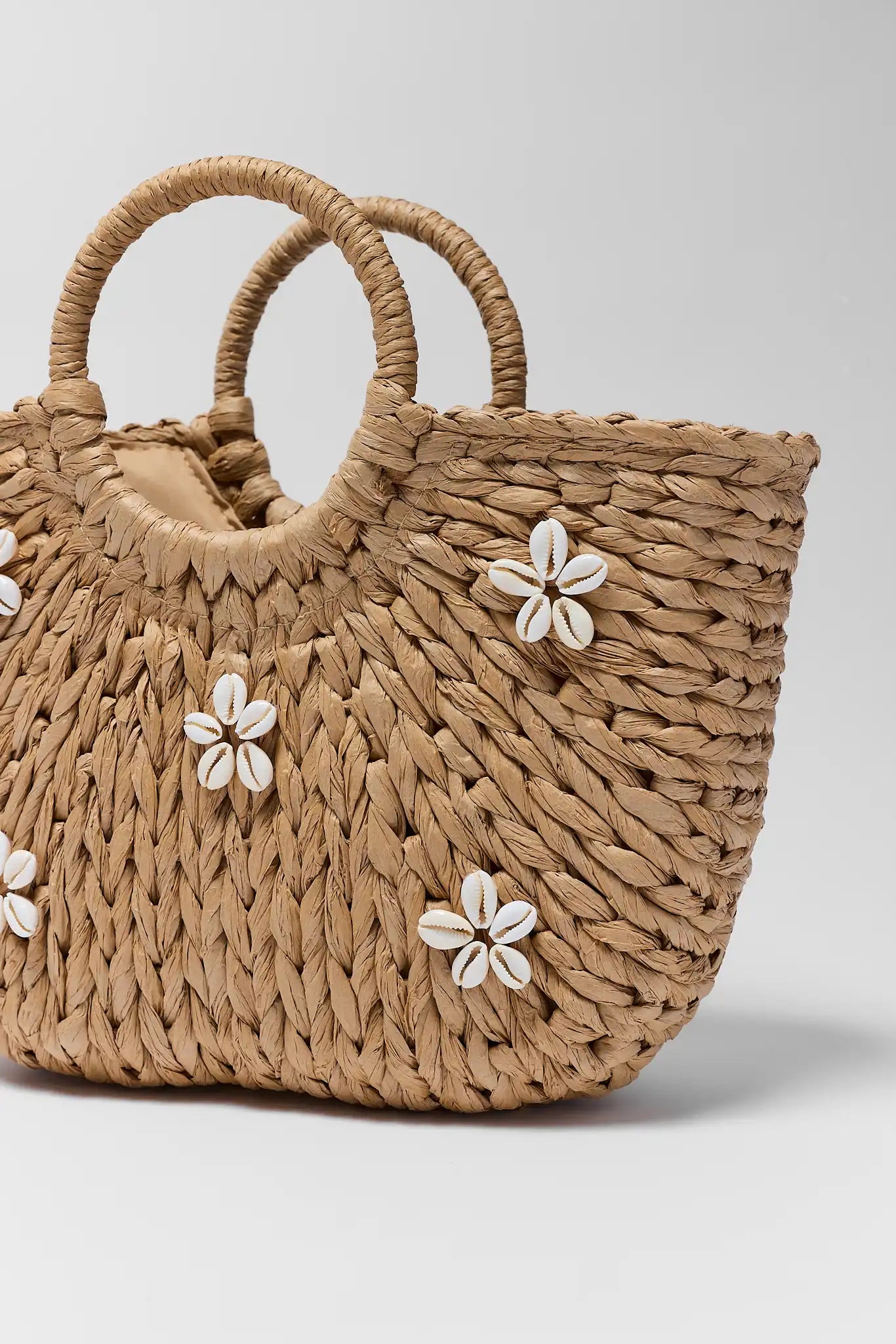 close up Woven handbag with floral decorations on a light gray background