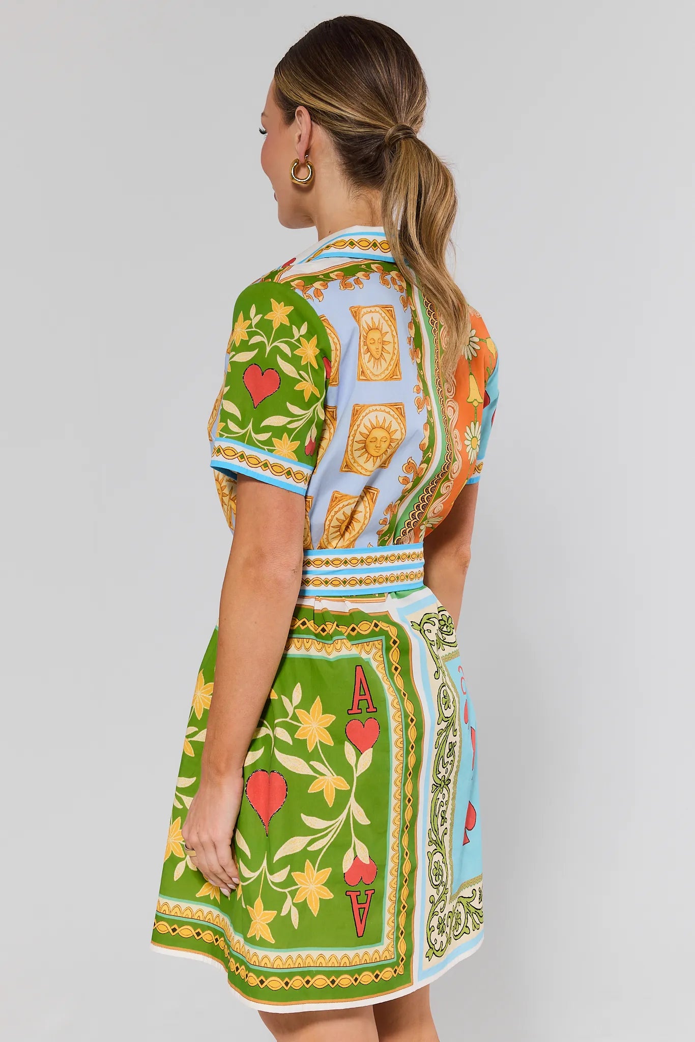 Woman standing wearing a colorful patterned dress on a gray background