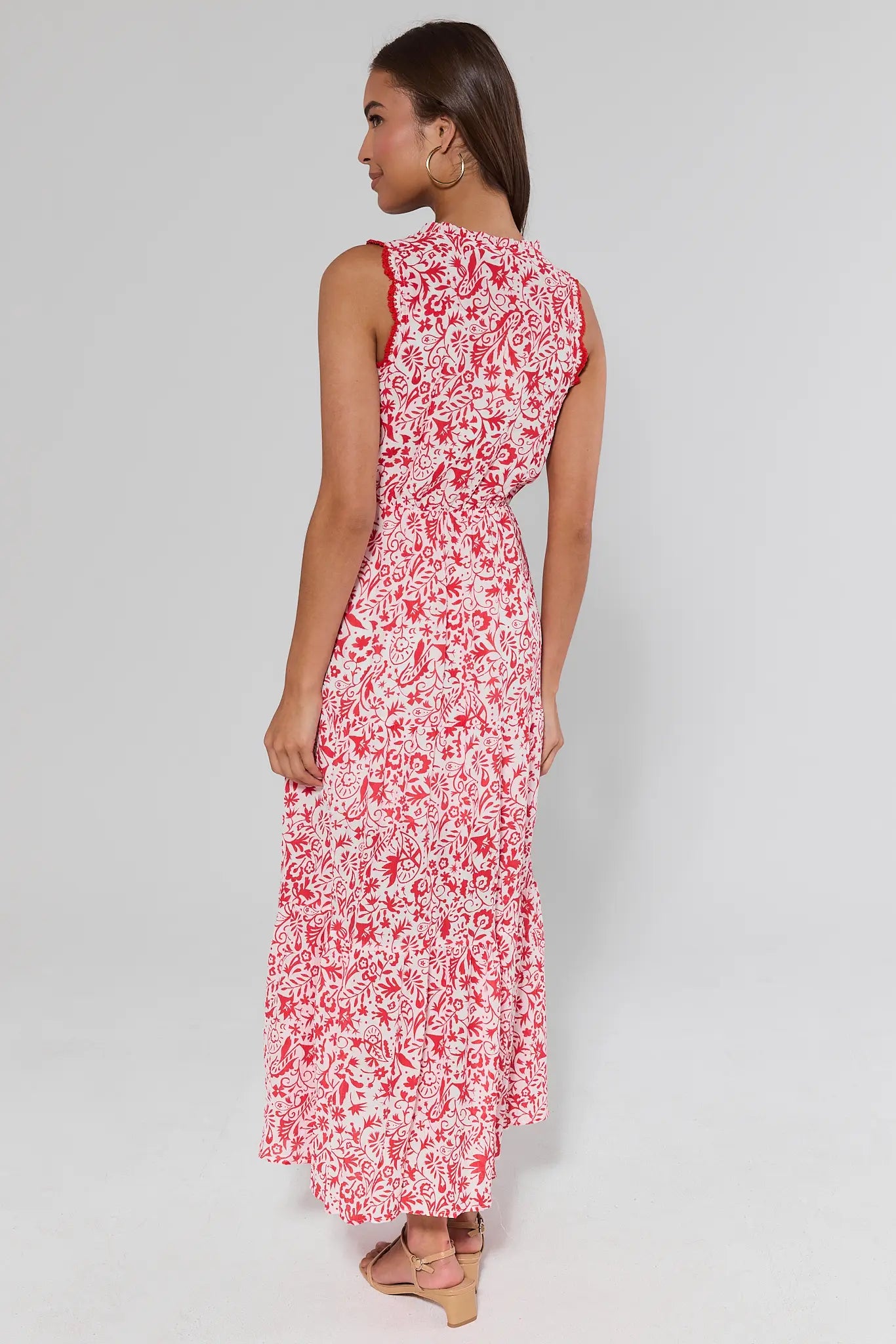 Woman standing wearing a red floral dress on a gray background