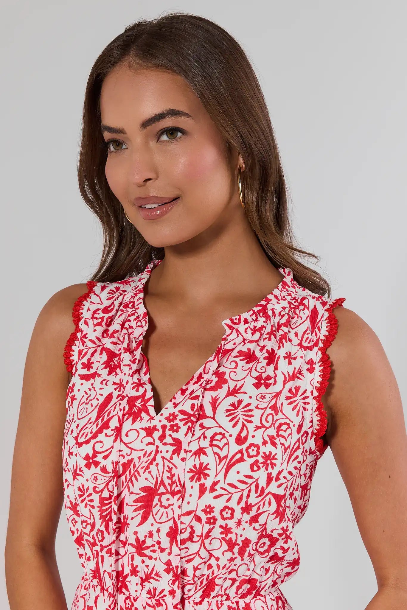 close up Woman wearing a red and white floral dress against a plain background