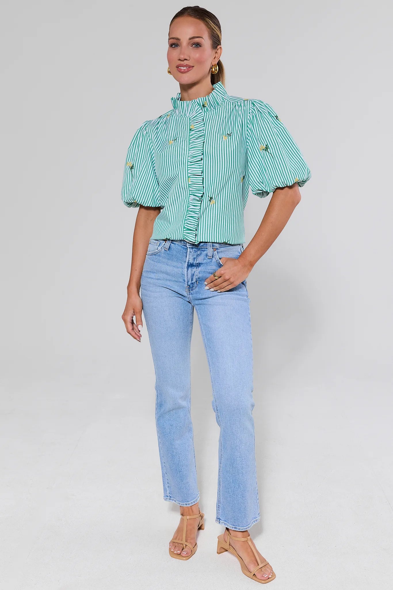 Woman wearing a green checkered blouse and light blue jeans on a white background