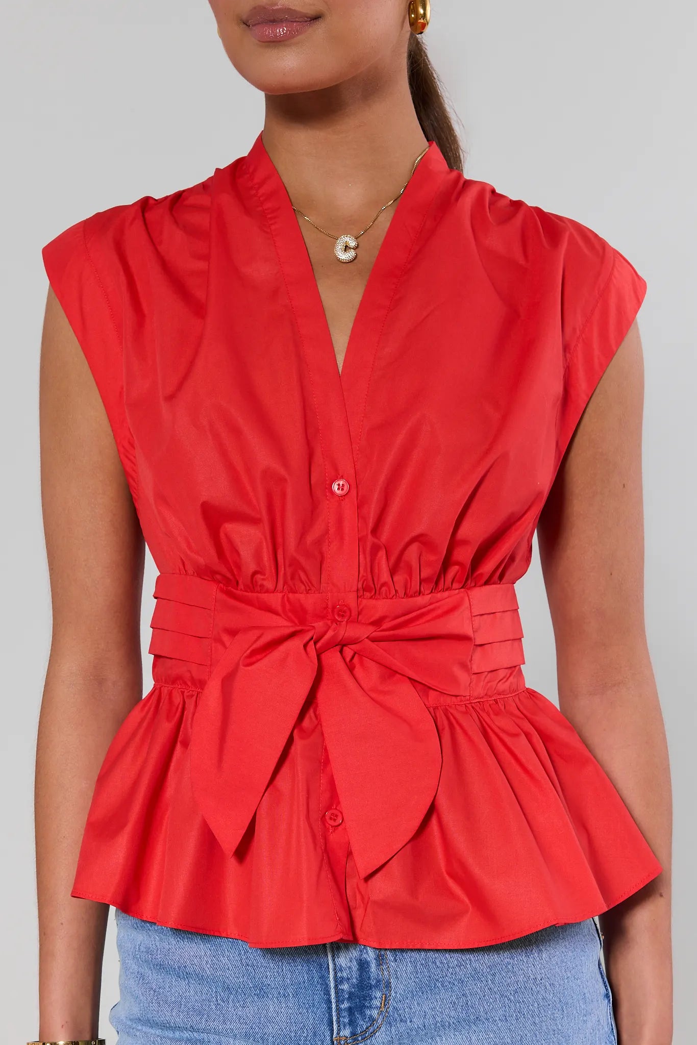 close up Red sleeveless top with a tie waist worn by a person on a gray background