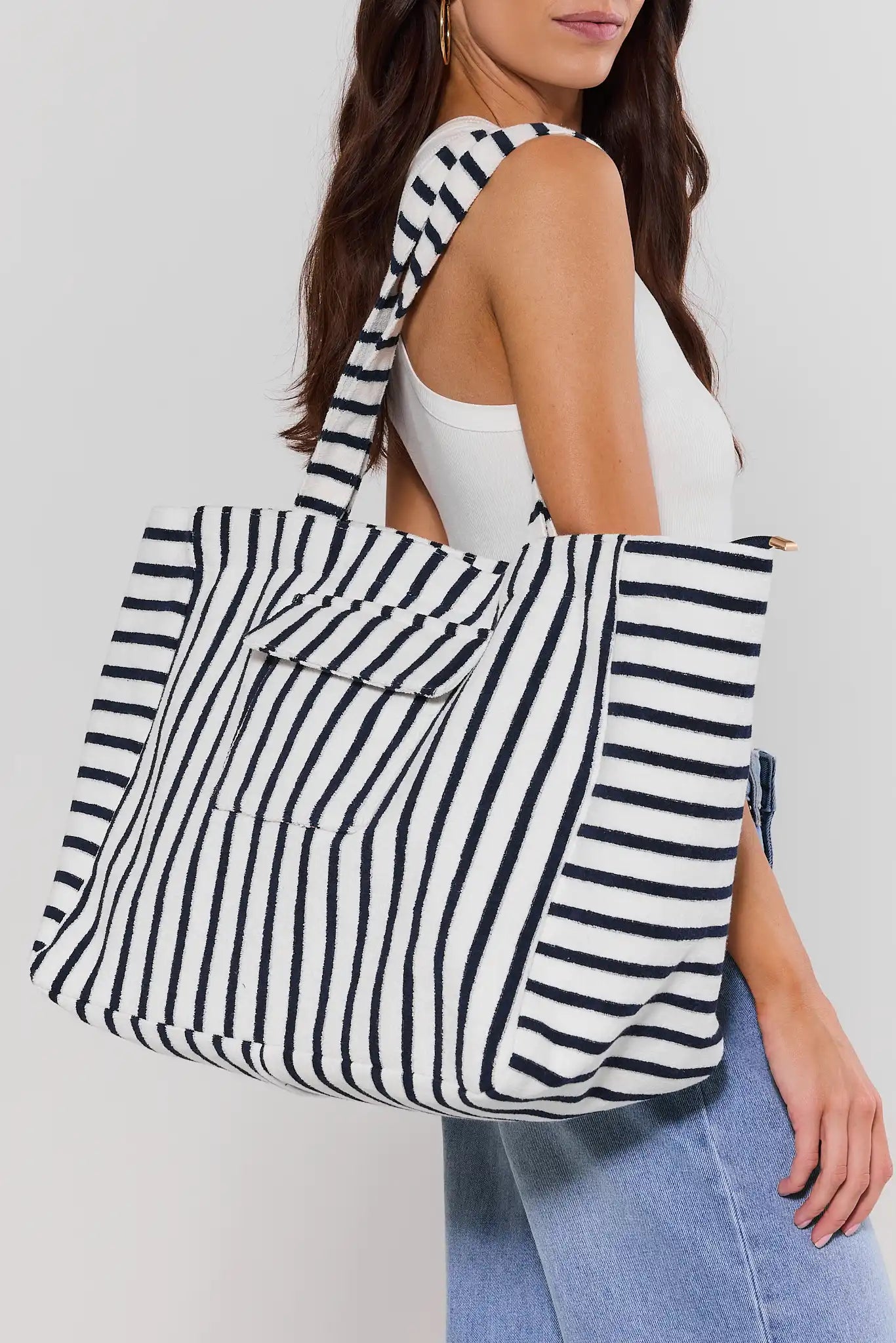 Woman carrying a black and white striped tote bag on a plain background