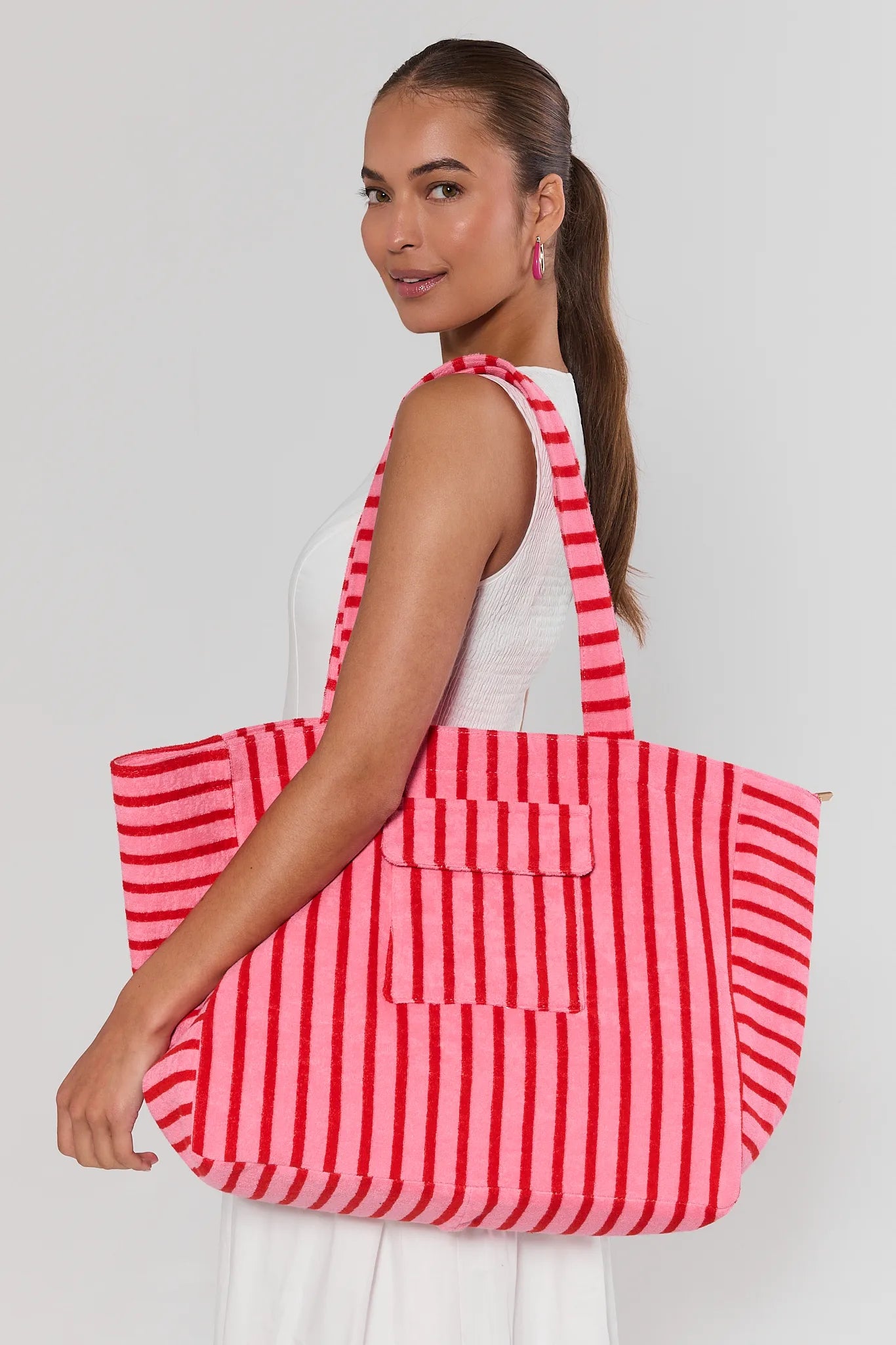 Woman holding a red and white striped tote bag against a plain background