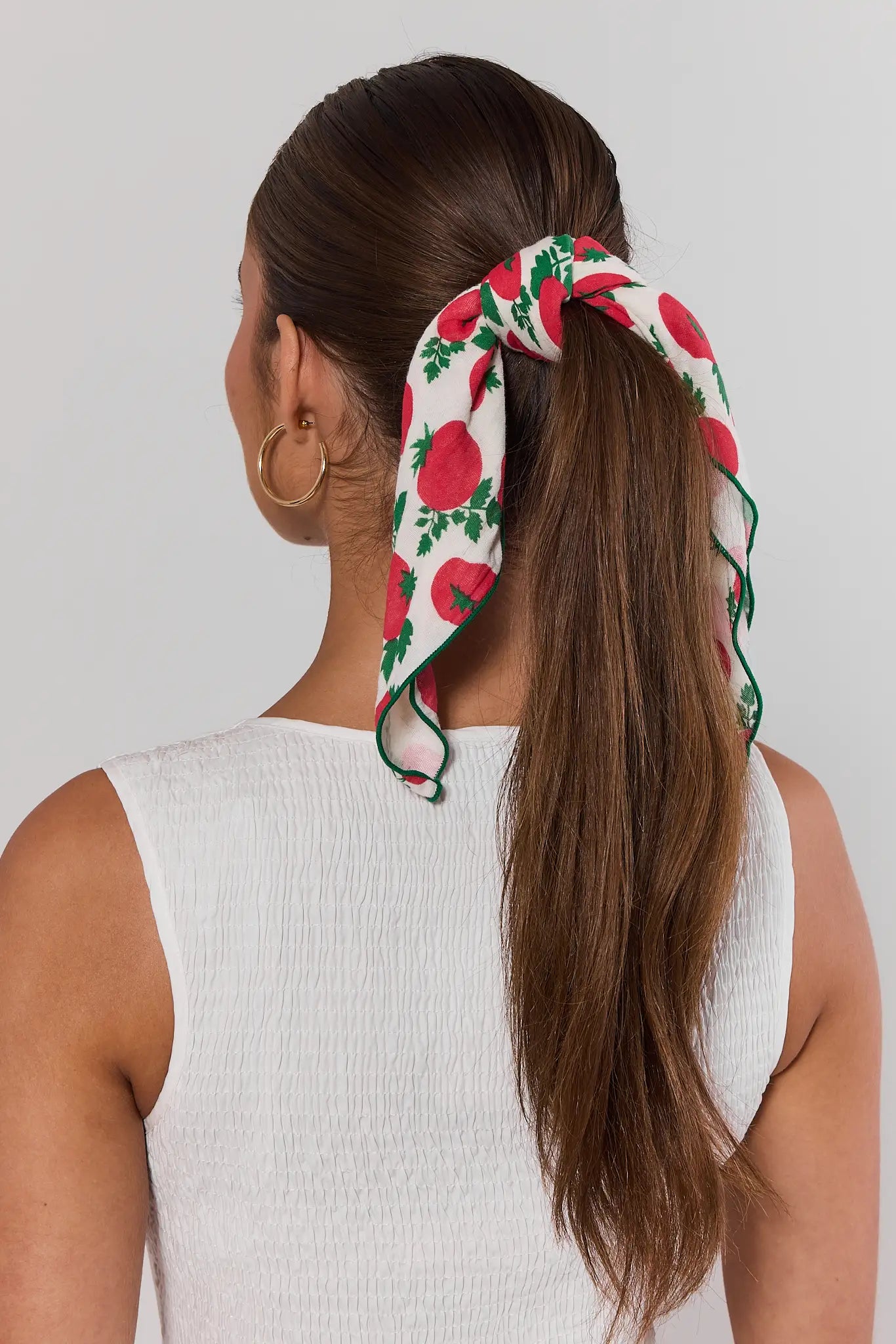Woman with a ponytail wearing a floral headband against a plain background