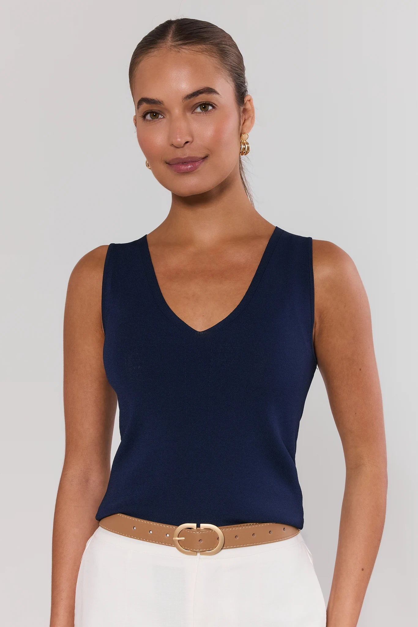 Woman wearing a navy blue sleeveless top with a white background