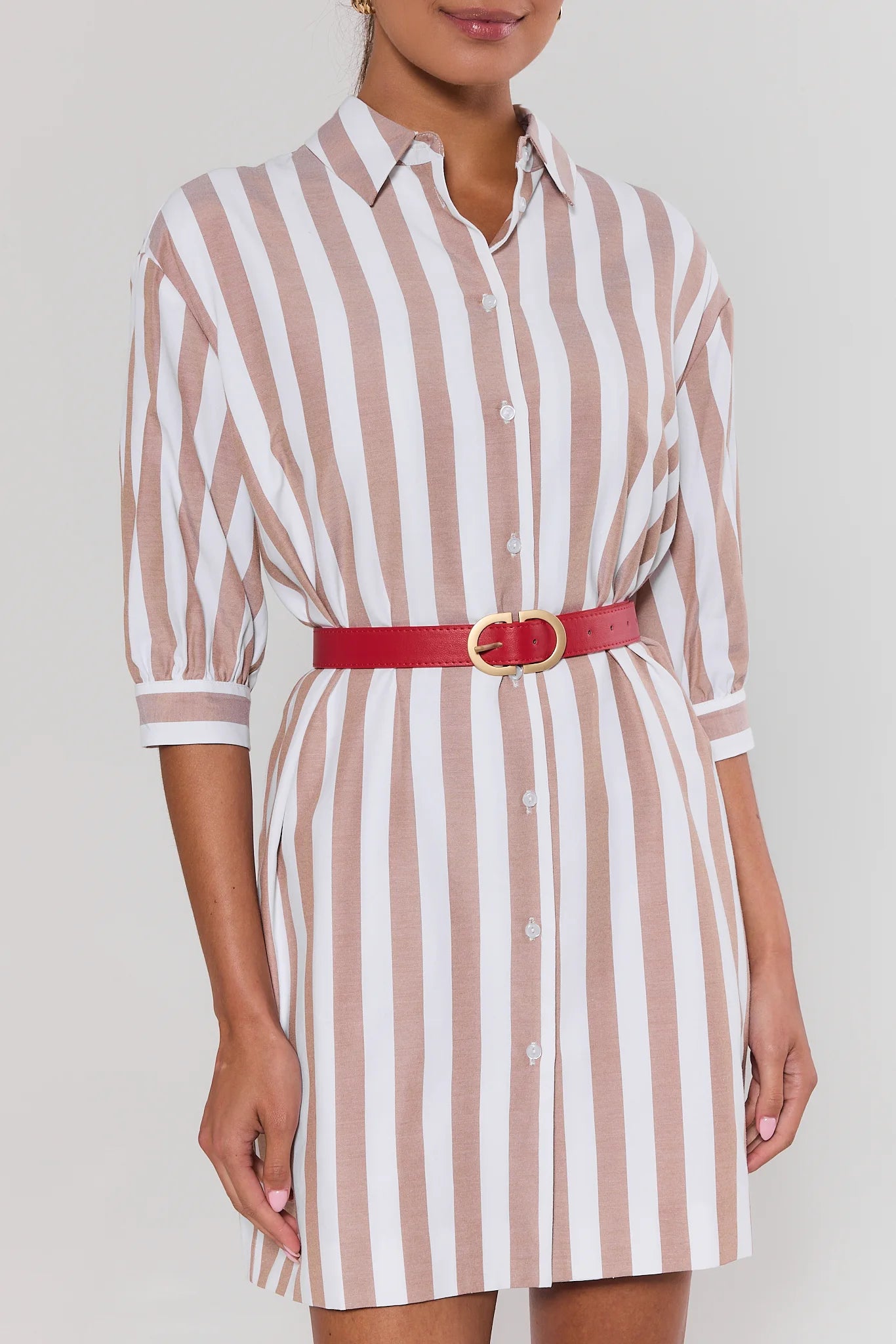 woman wearing stripe dress and Red belt with a gold buckle on a light gray background