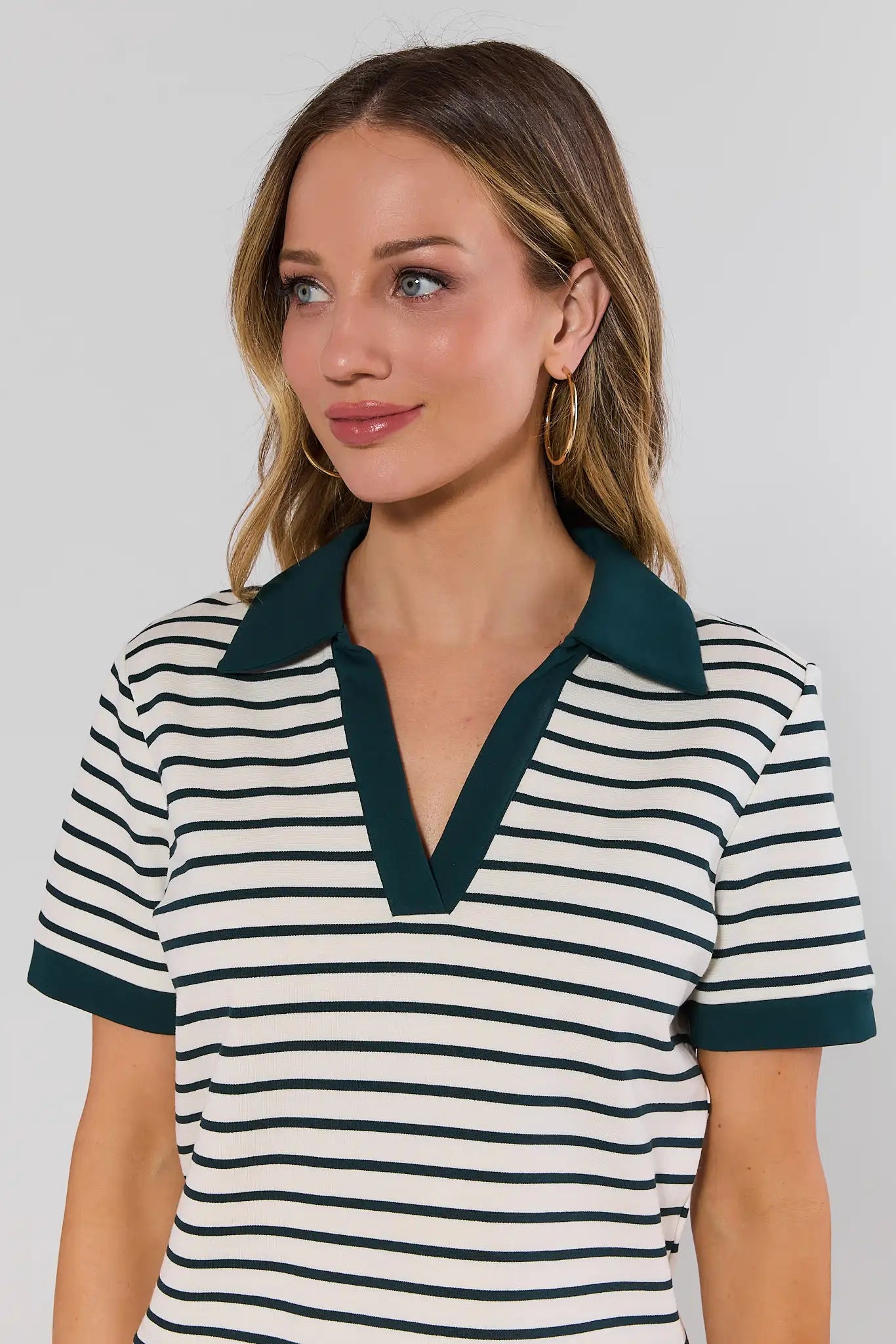 close up Woman wearing a striped shirt with a green collar against a plain background