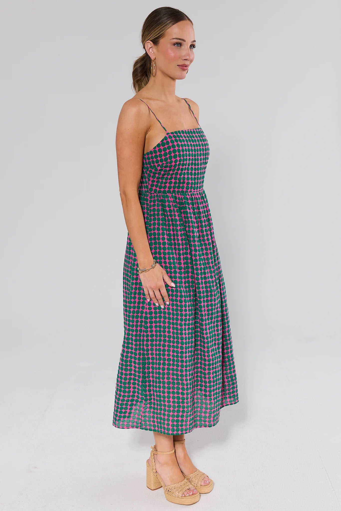side shot Woman wearing a green and pink plaid dress against a white background