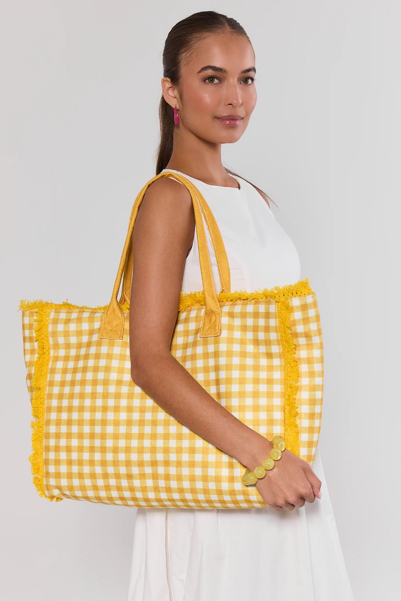 Woman holding a yellow gingham bag against a white background