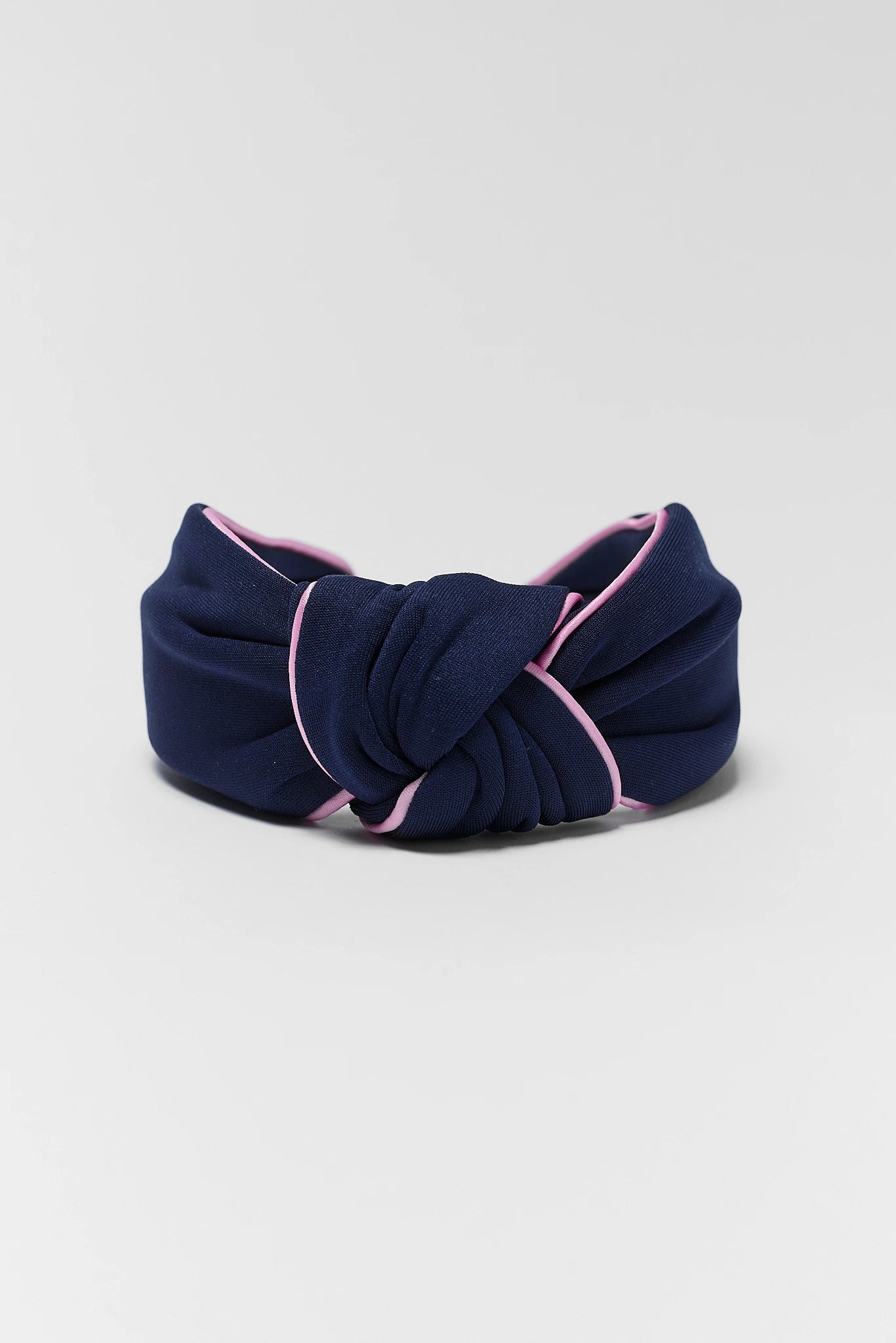 close up Navy blue headband with pink trim on a light gray background