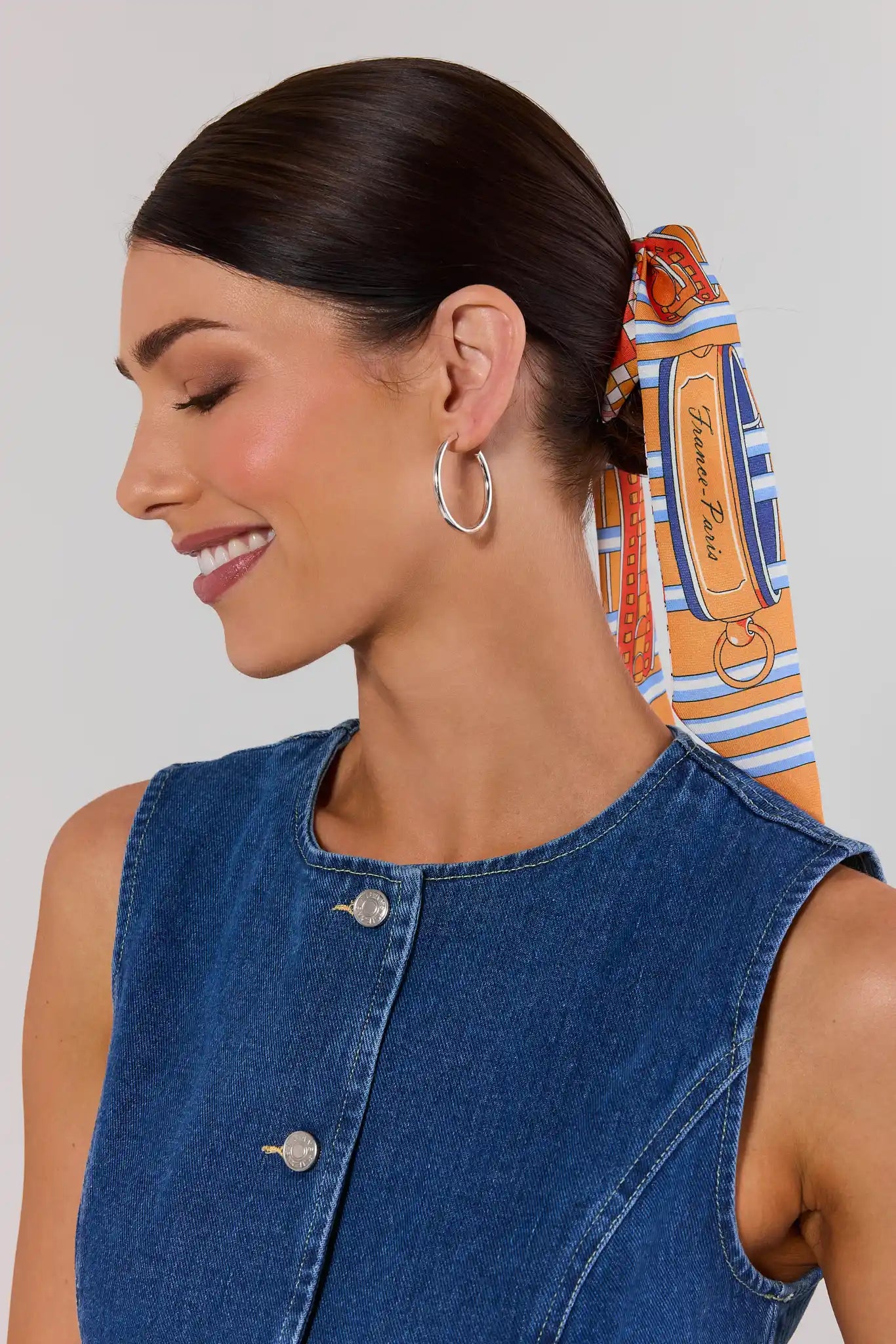 Woman wearing hoop earrings with a colorful hair tie in the background