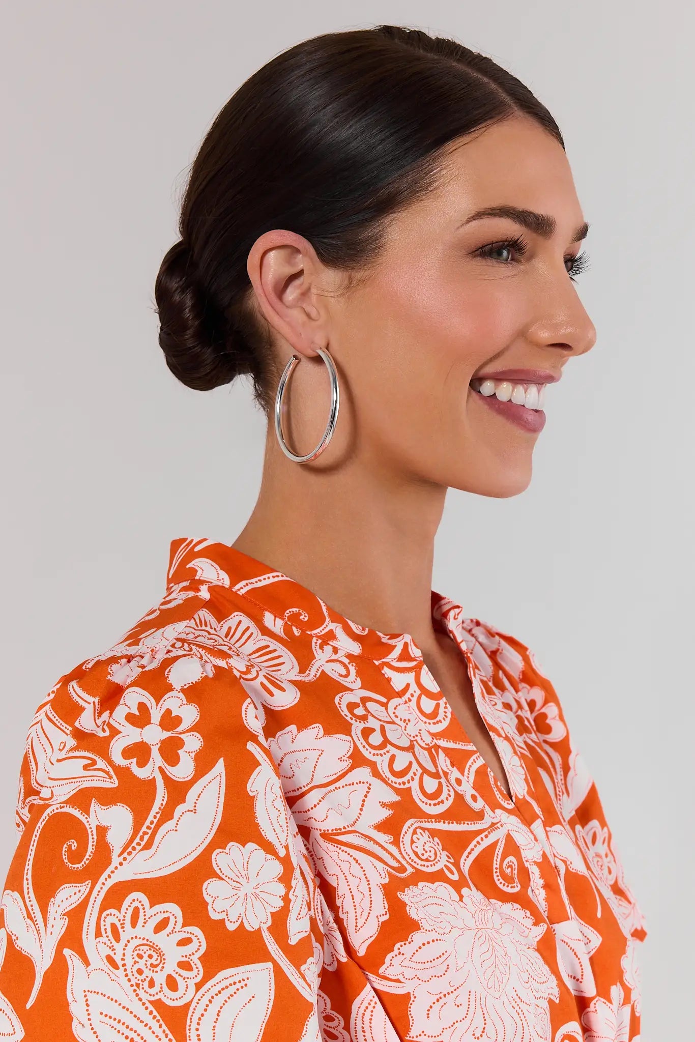 Woman wearing large hoop earrings with a white background