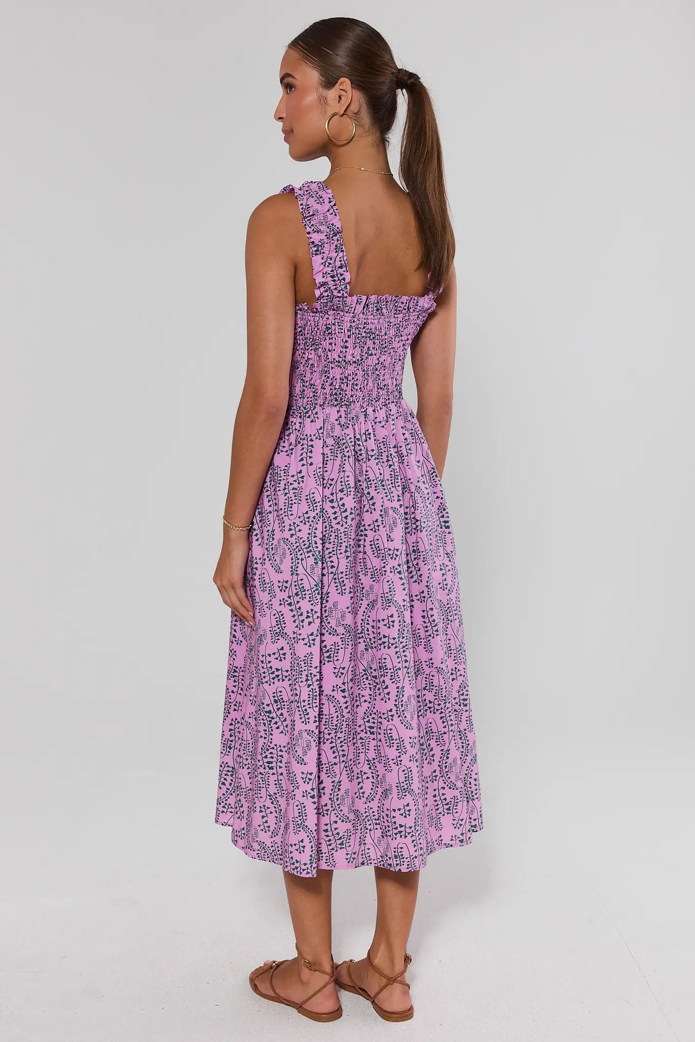 Woman wearing a purple patterned dress on a white background standing