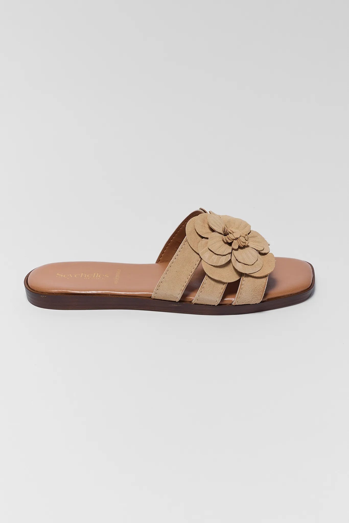 one Beige sandal with a flower detail on a light gray background