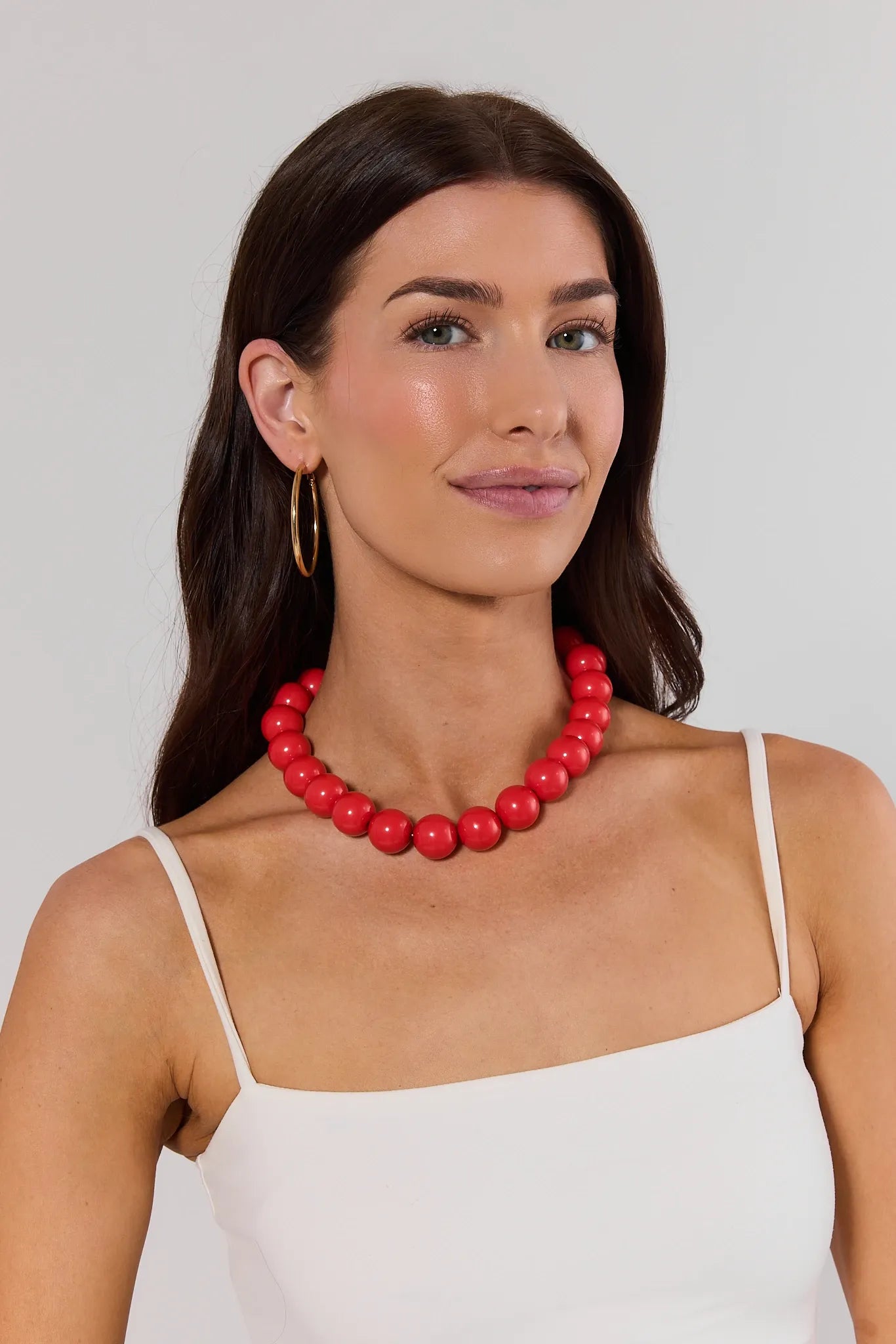 woman wearing Red beaded necklace on a light gray background