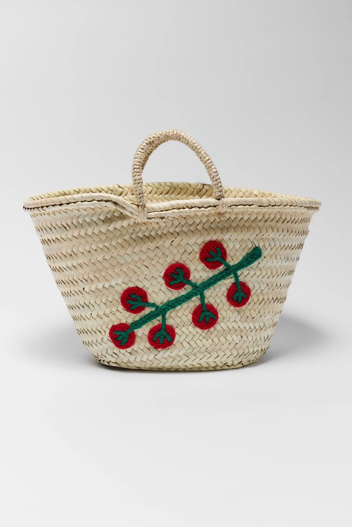 Woven basket with red floral design on a white background