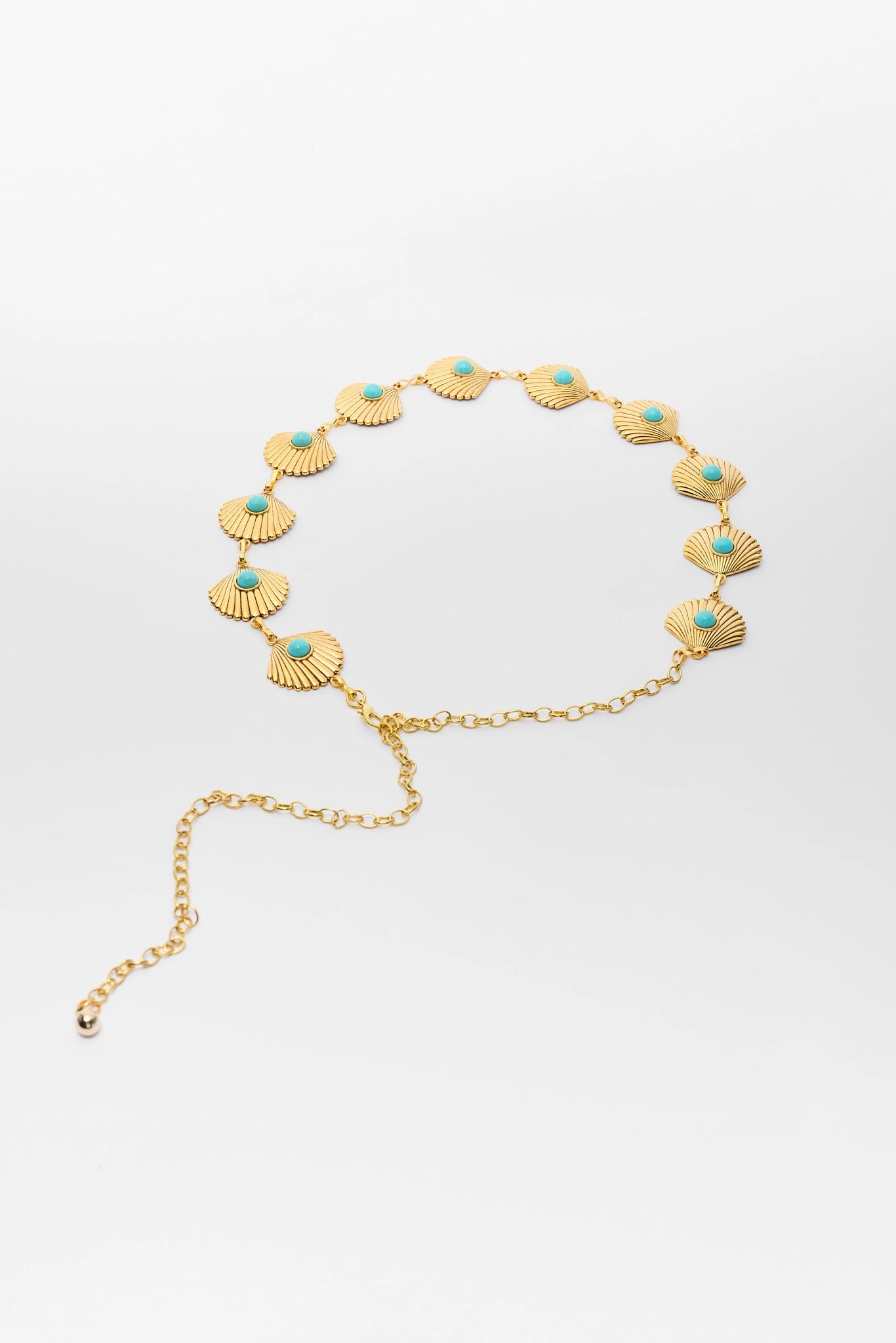 Gold necklace with shell and turquoise stone accents on a white background