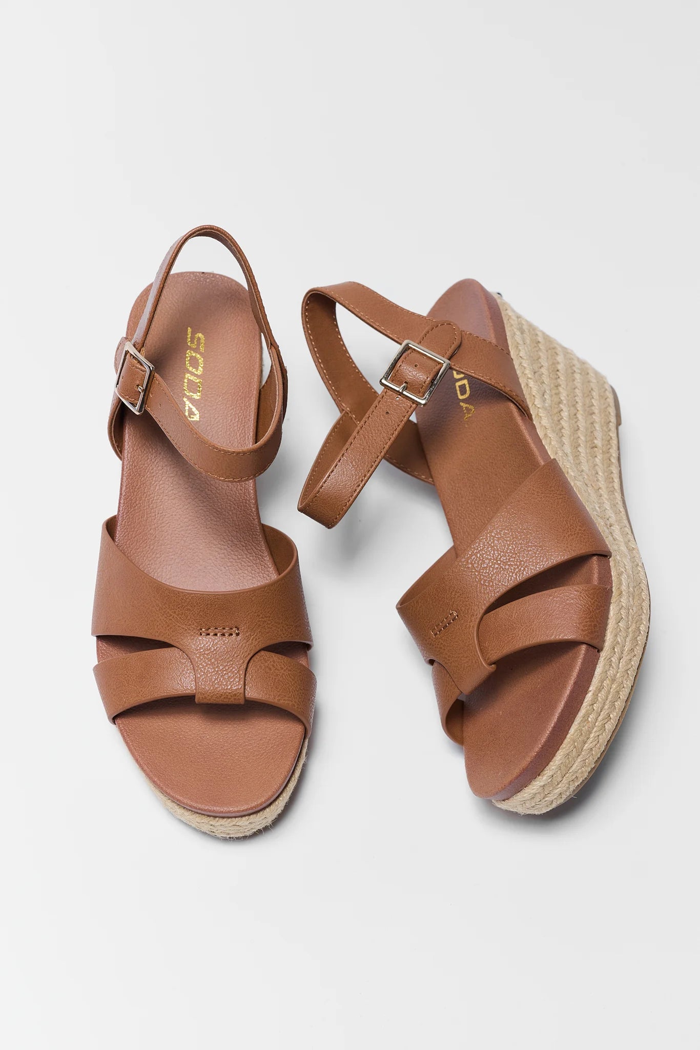 Pair of dark brown sandals with espadrille sole on a light gray background