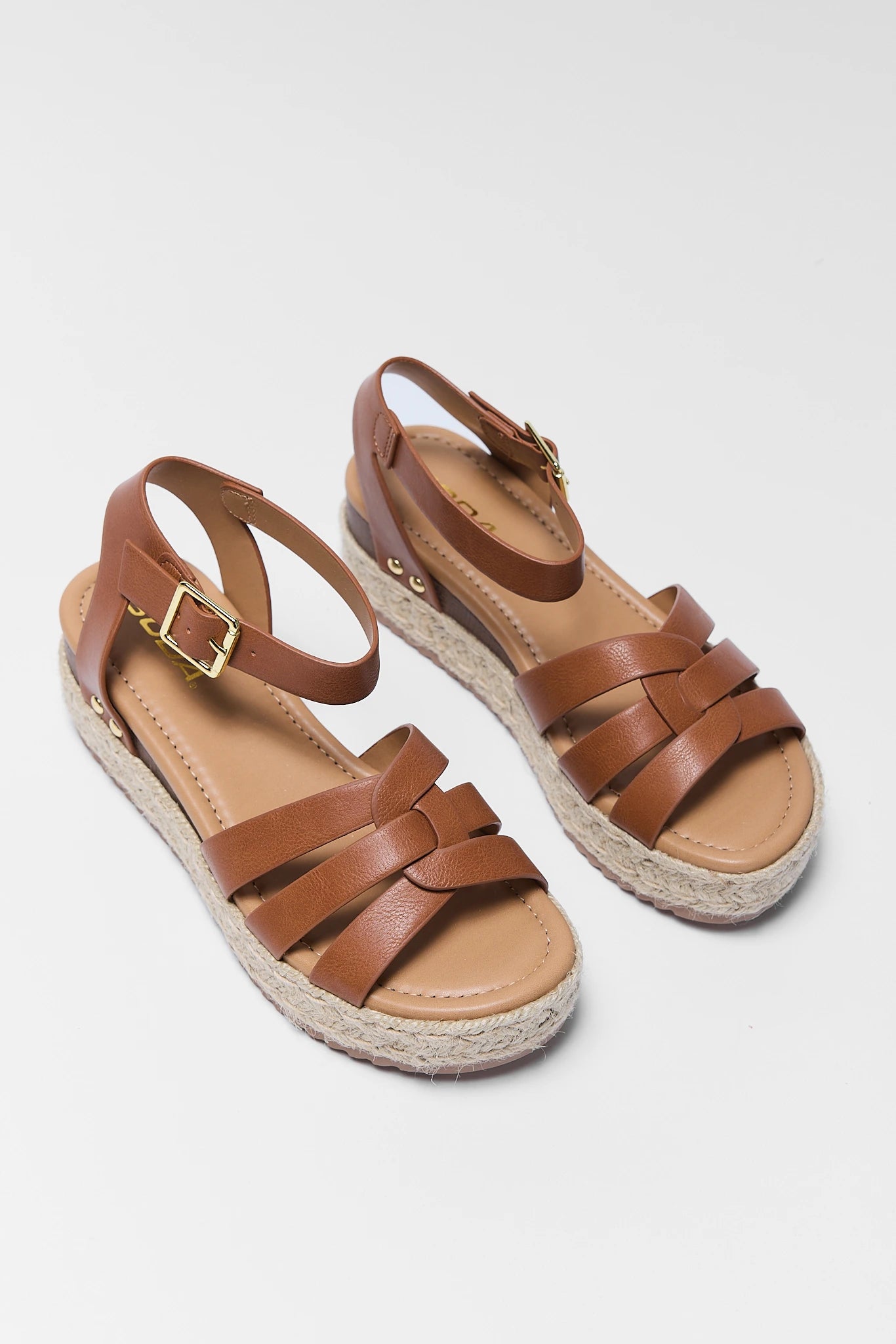 Pair of two brown sandals with espadrille sole on a light gray background