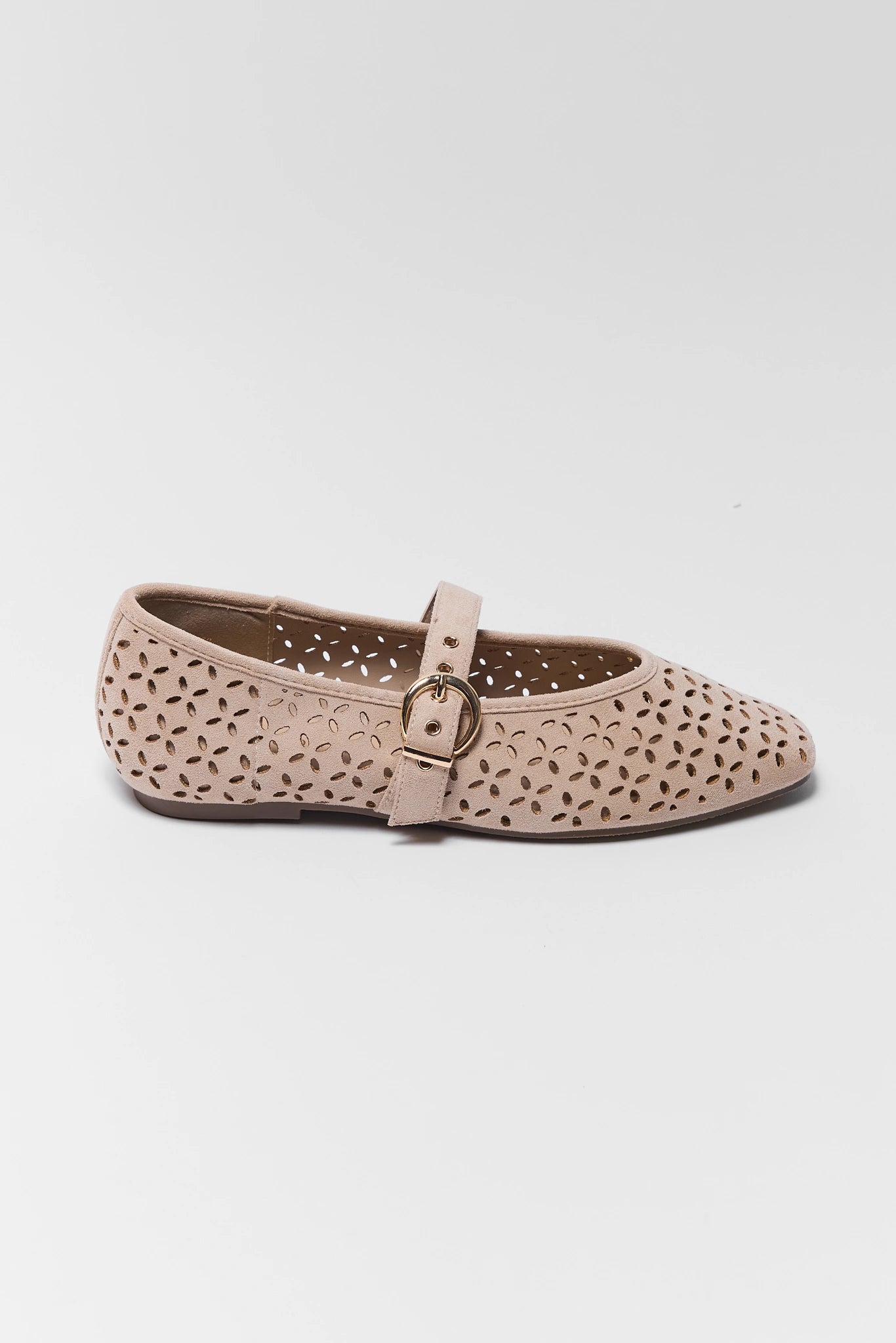 A single women's flat shoe in a light beige or blush pink color, featuring a perforated cutout pattern across the upper and a matching strap with a small metallic buckle, shown against a plain light gray background.