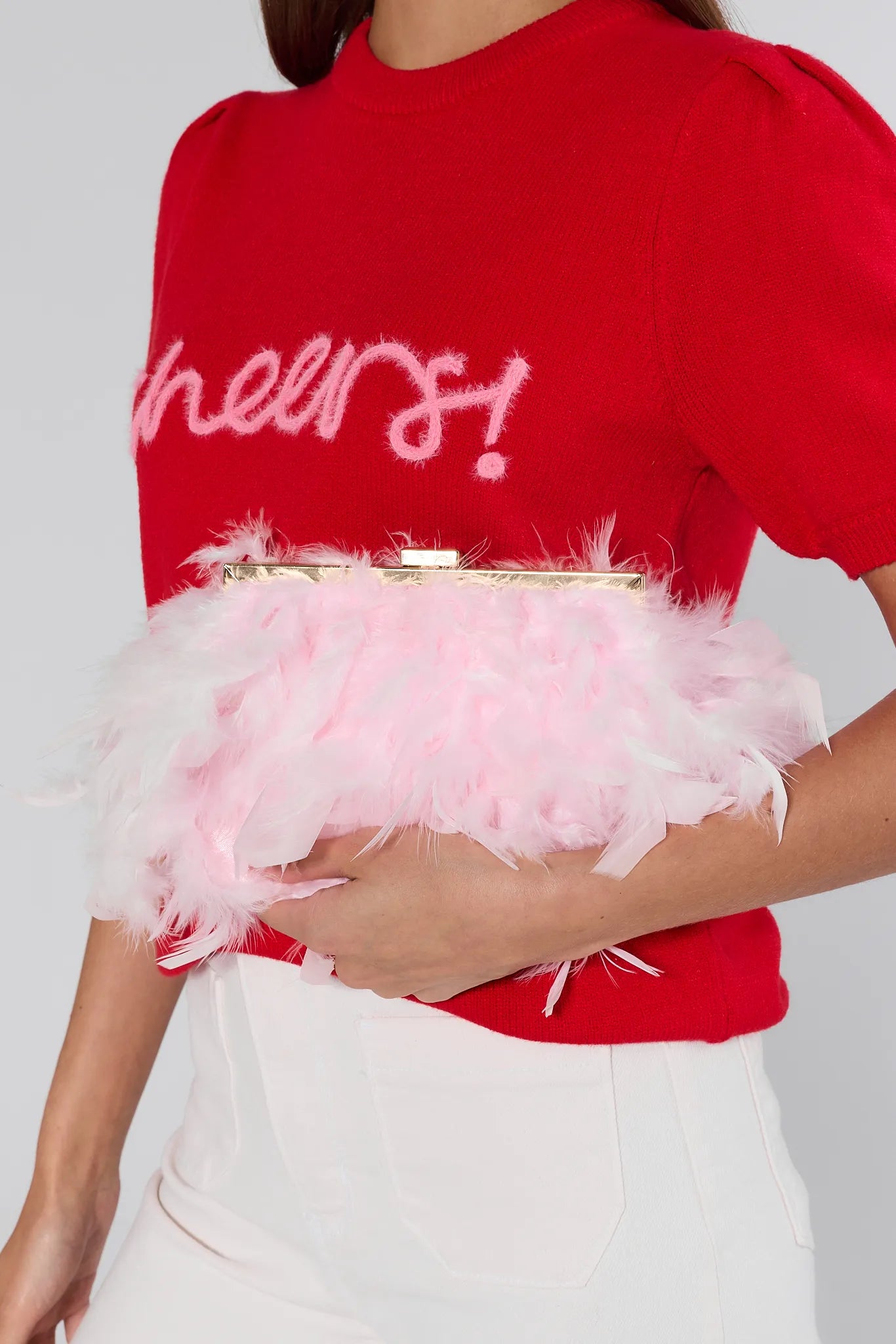 Red sweater with fluffy pink trim worn by a person on a plain background