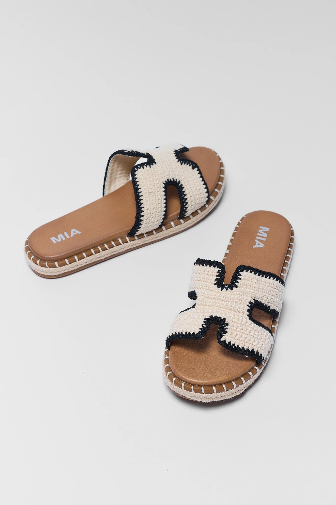 Pair of sandals with woven design and brown soles on a light gray background