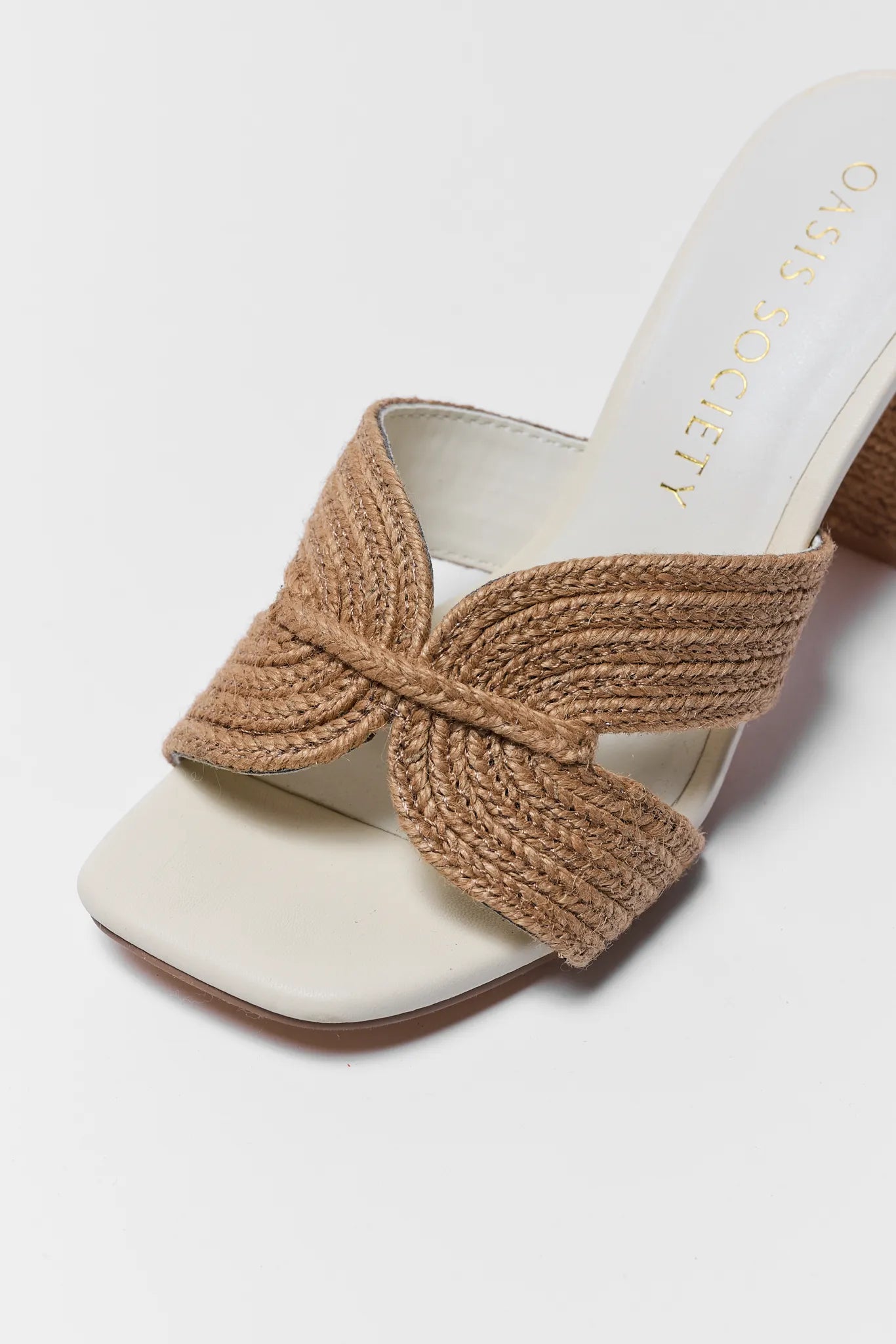 White sandal with a brown woven bow on a light gray background
