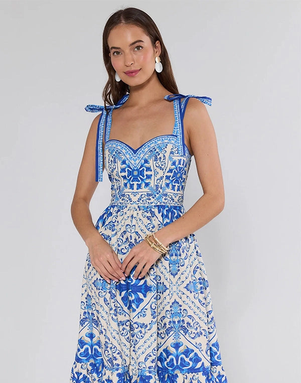 Woman wearing a blue and white patterned dress with bow straps on a plain background