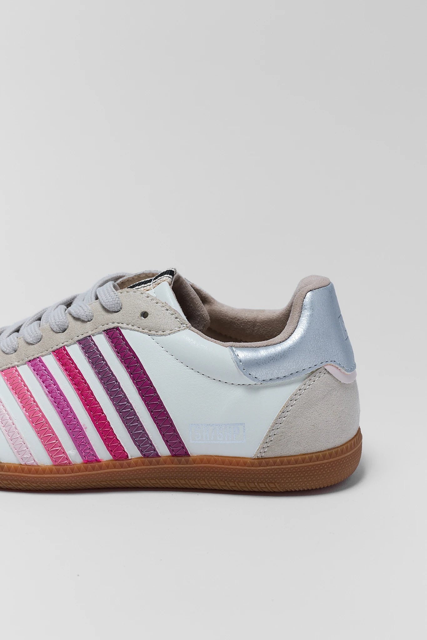 close up White sneaker with pink and purple stripes on a light gray background