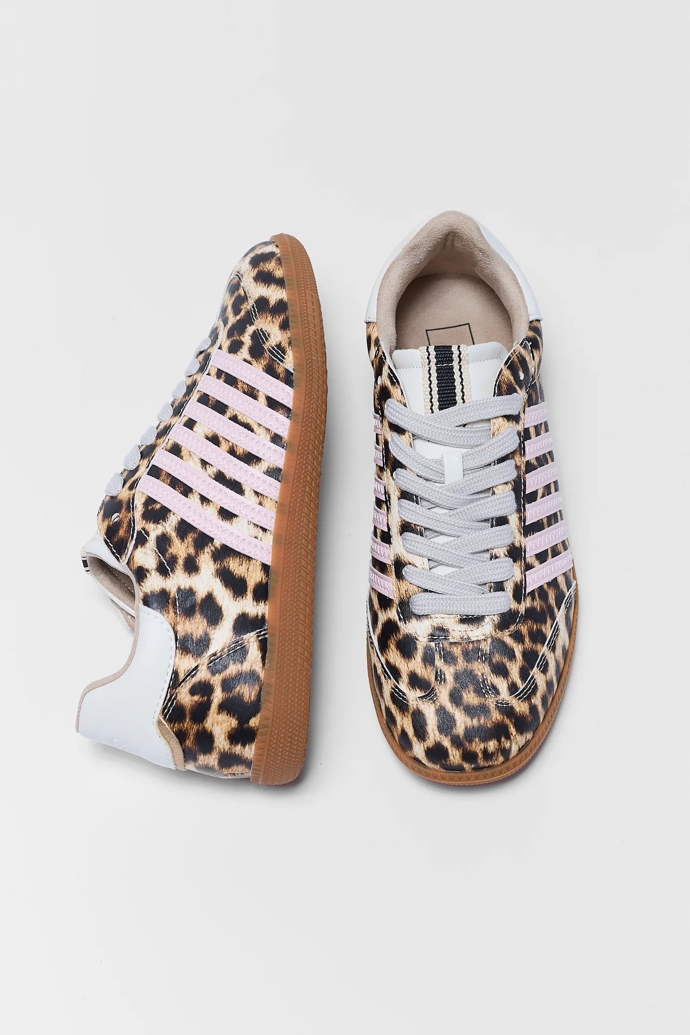 A pair of low-top sneakers with a leopard print pattern, featuring light pink three stripes, white laces, and white toe caps on a light gray background.