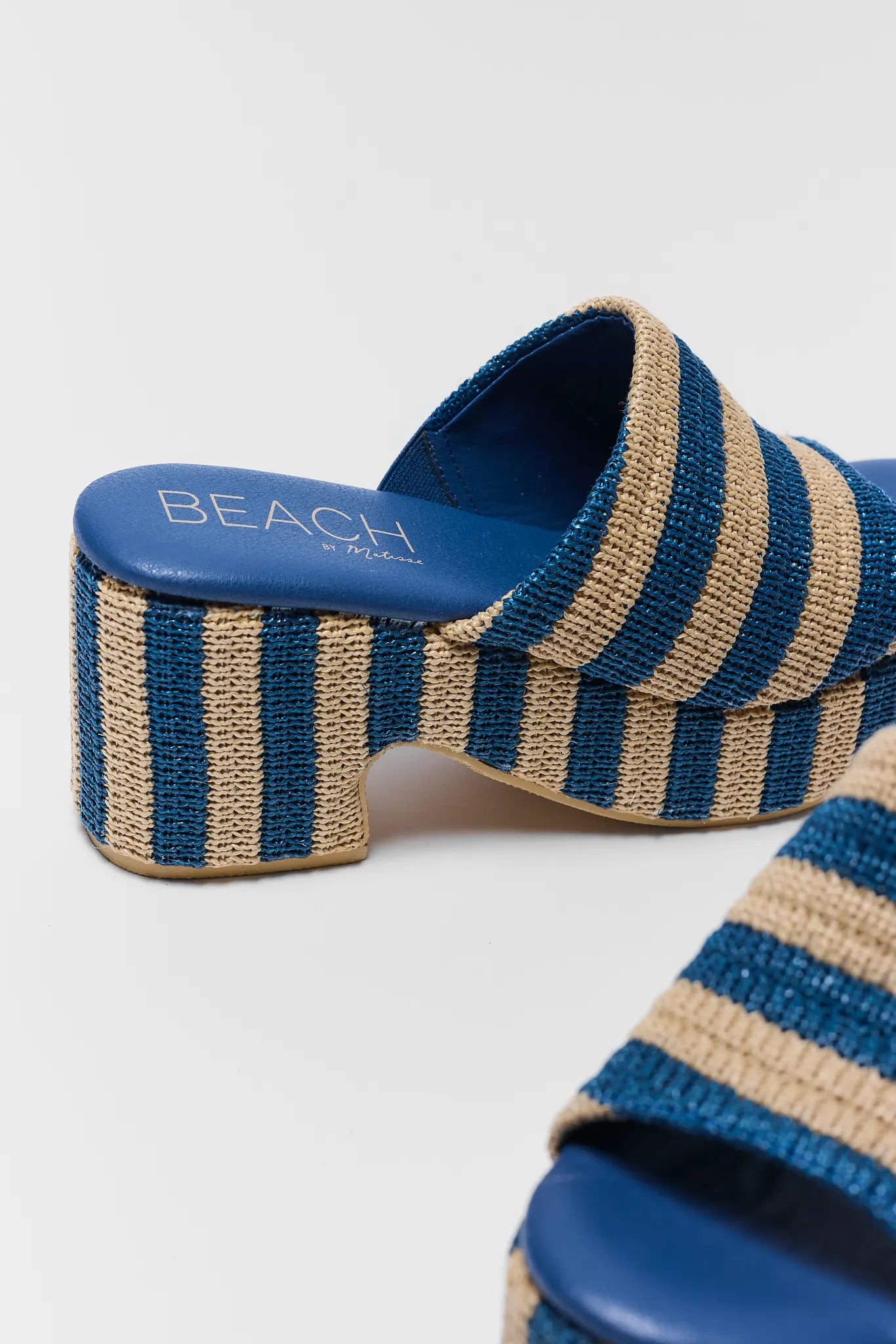 Blue and beige striped sandals with text on a white background close up