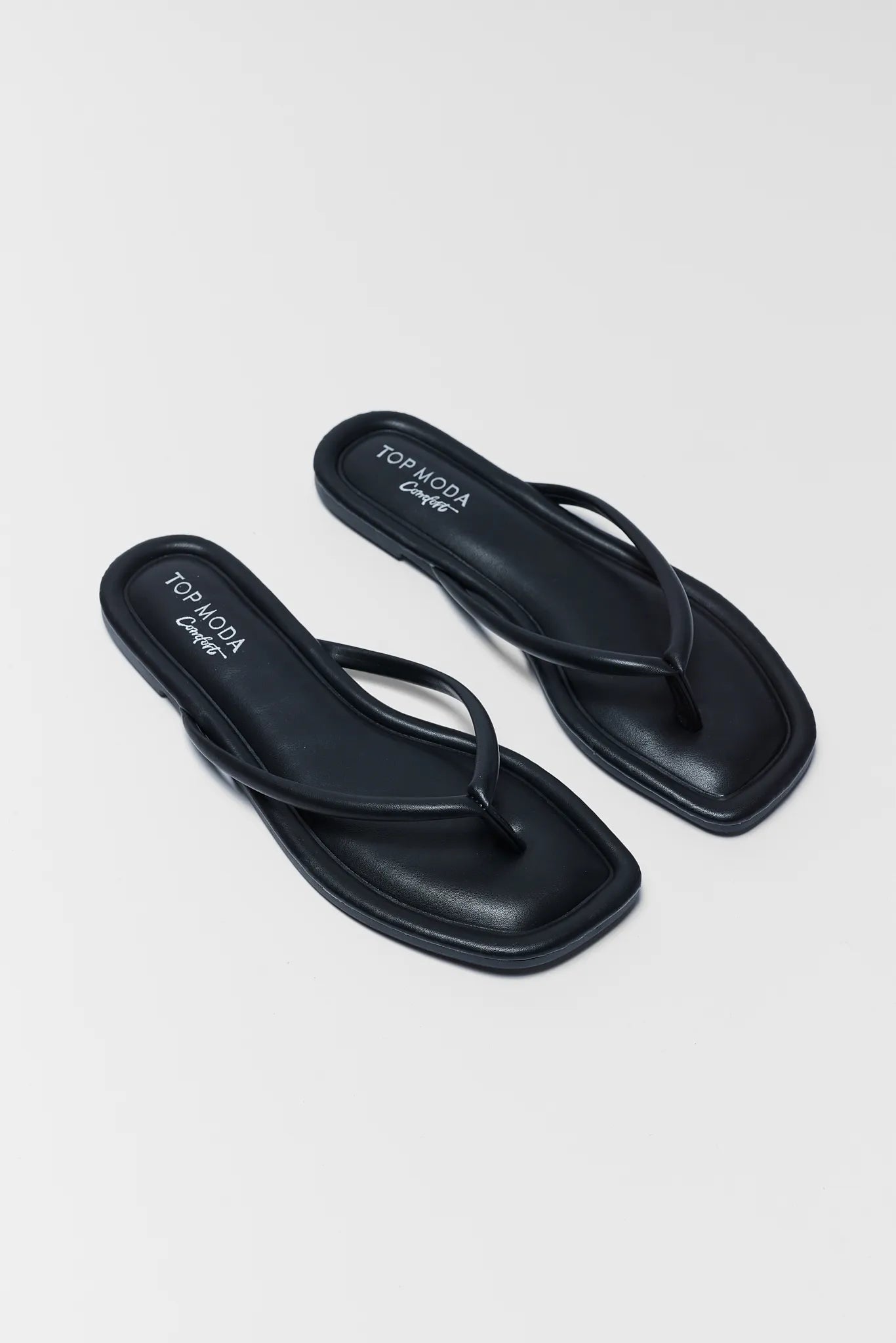 Pair of black flip-flops on a light gray background