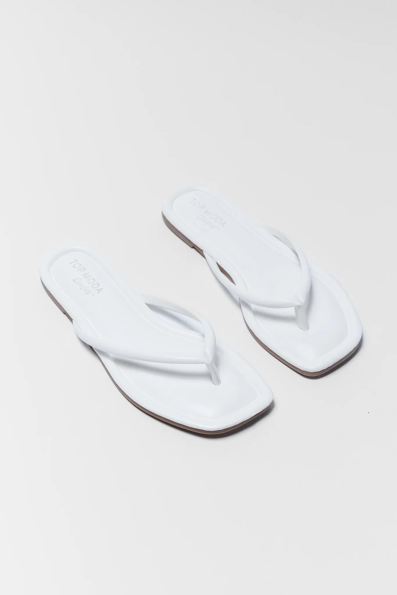 Pair of white slippers on a light gray background