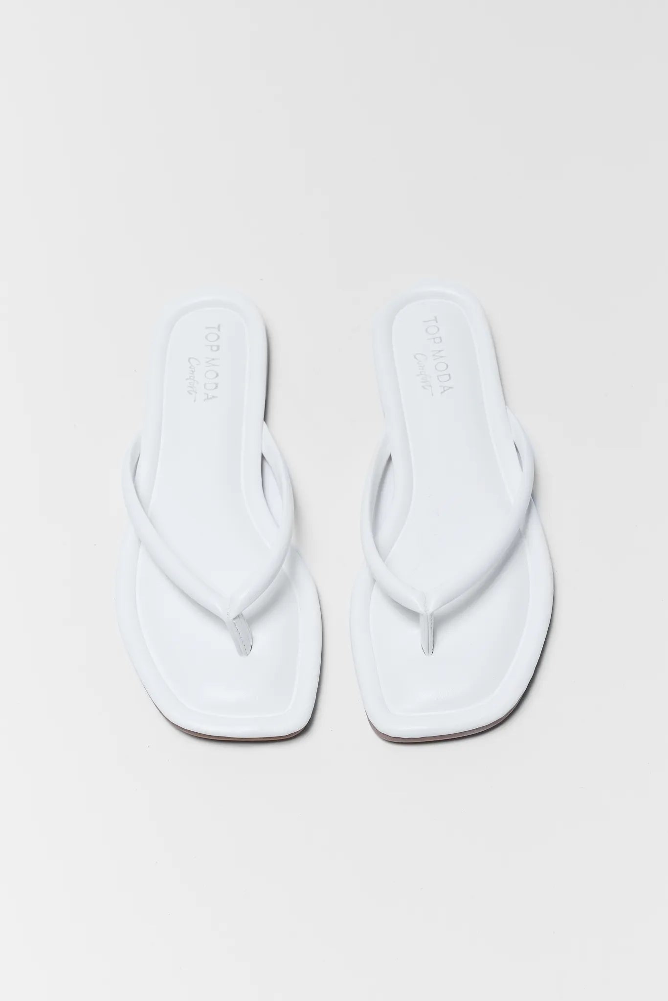 Pair of white flip-flops on a light gray background