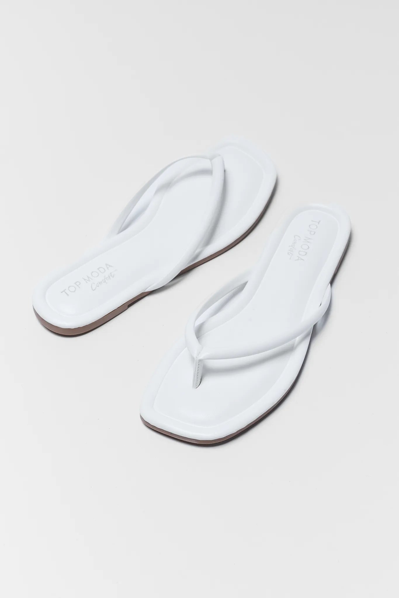 Pair of white flip-flops on a light gray background