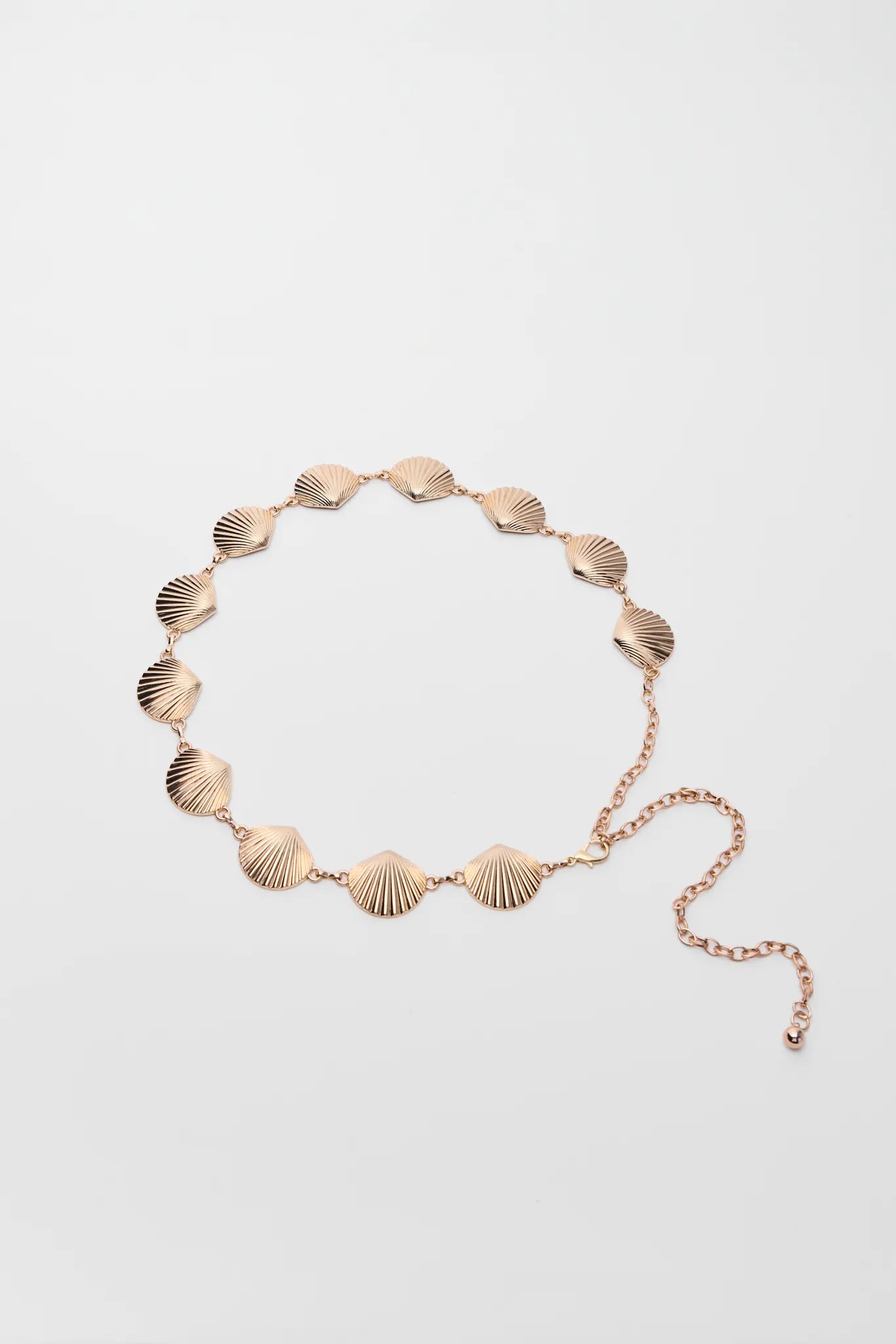 Gold bracelet with shell-shaped links on a light gray background